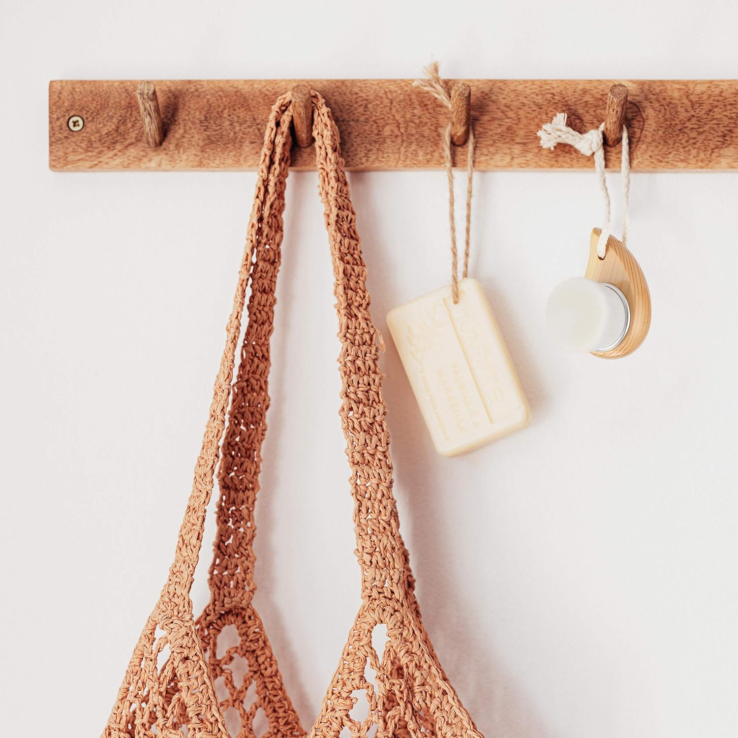 Ein Holzhaken mit einer beigen Häkeltasche, Seife und Bürste.