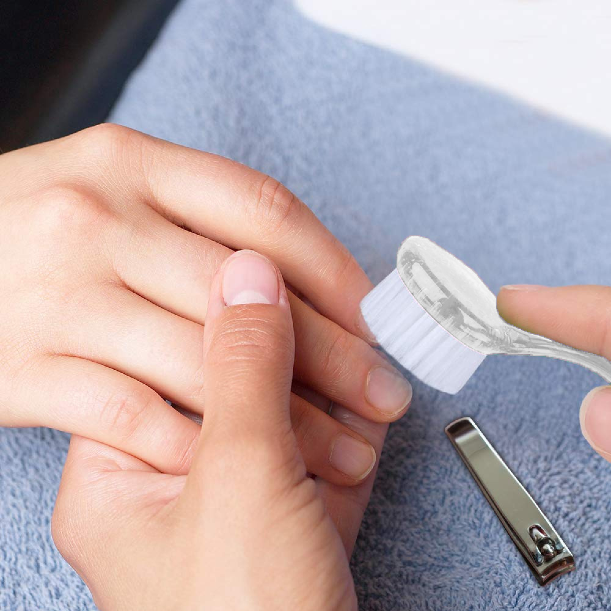 Eine Hand wird mit einer Bürste behandelt, daneben liegt ein Nagelknipser.