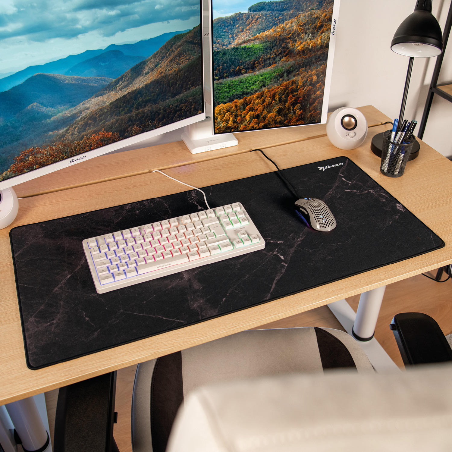 Ein Schreibtisch mit zwei Monitoren, Tastatur, Maus, Lampe und einem Stiftehalter.