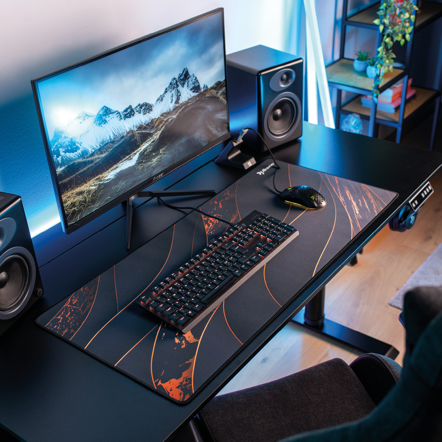 Ein moderner Schreibtisch mit Monitor, Tastatur, Maus und Lautsprechern. Berglandschaft auf dem Bildschirm.