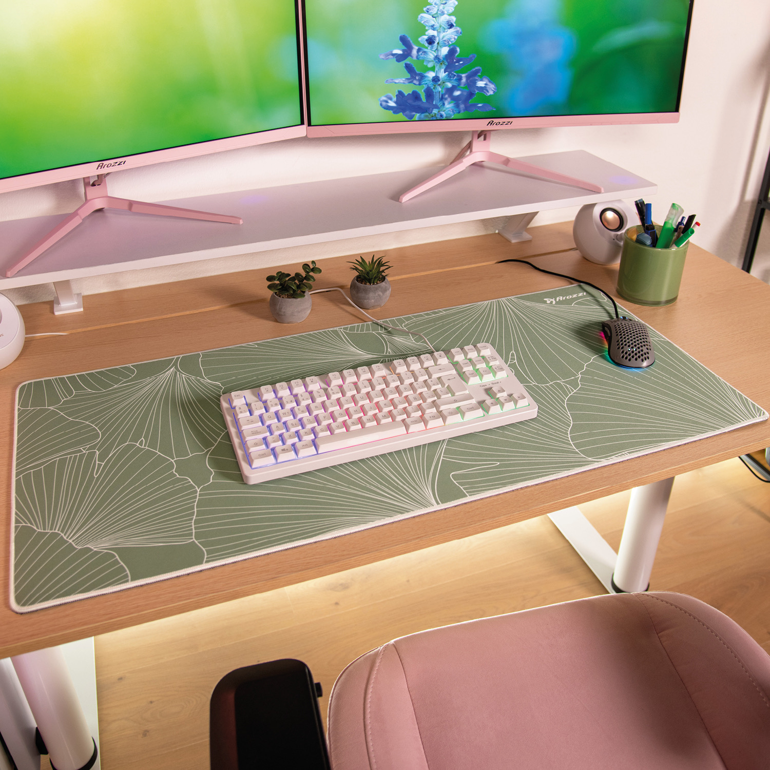 Ein Schreibtisch mit zwei Monitoren, Tastatur, Maus, Pflanzen und Stiften.
