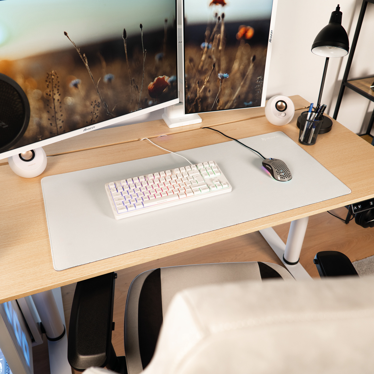 Moderne Schreibtisch-Einrichtung mit zwei Monitoren, weißer Tastatur, Maus und Lautsprechern.