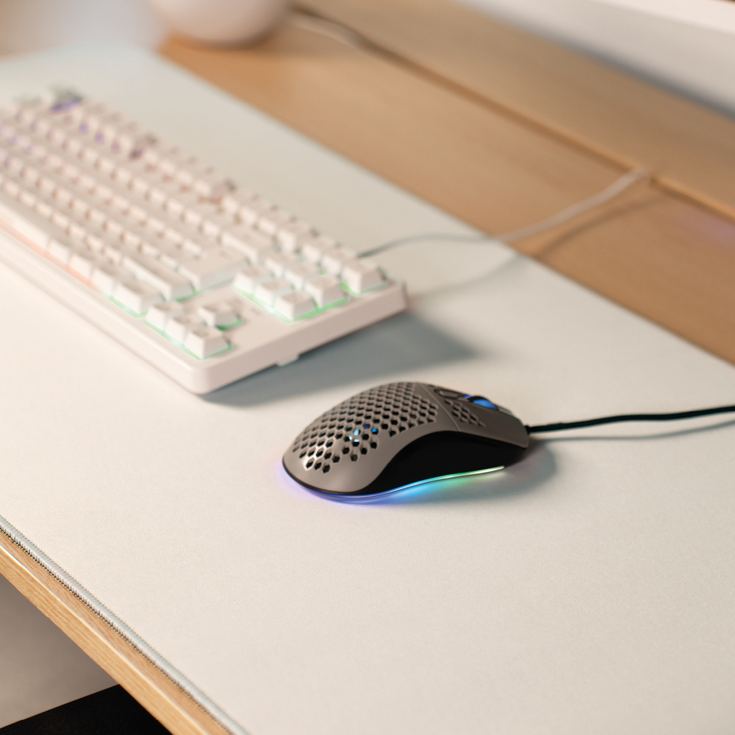 Graue Computermouse und weiße Tastatur auf weißer Unterlage, RGB-Beleuchtung.