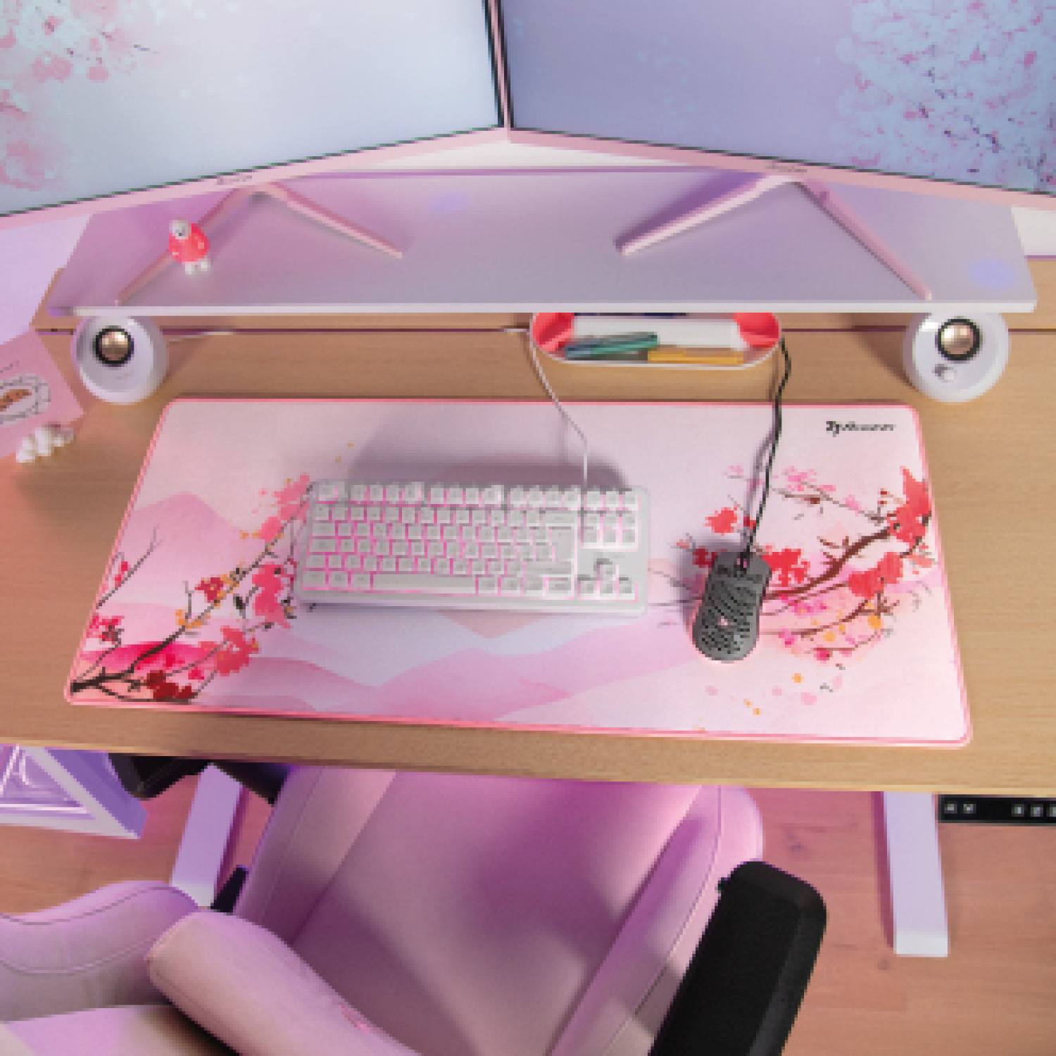 Ein rosa Schreibtisch mit Tastatur, Maus und Kirschblüten-Mauspad.