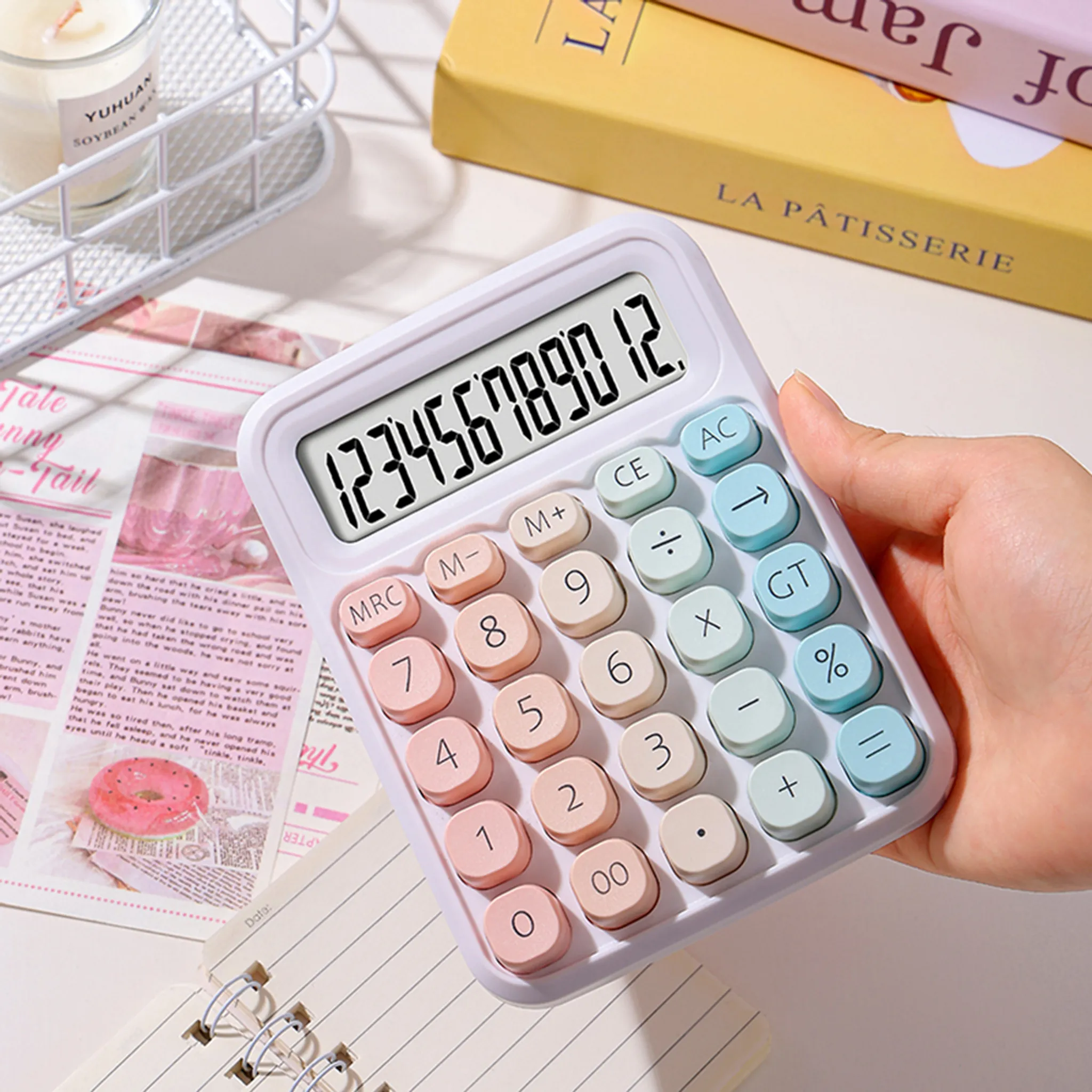 Eine Hand hält einen weißen Taschenrechner mit bunten Tasten.
