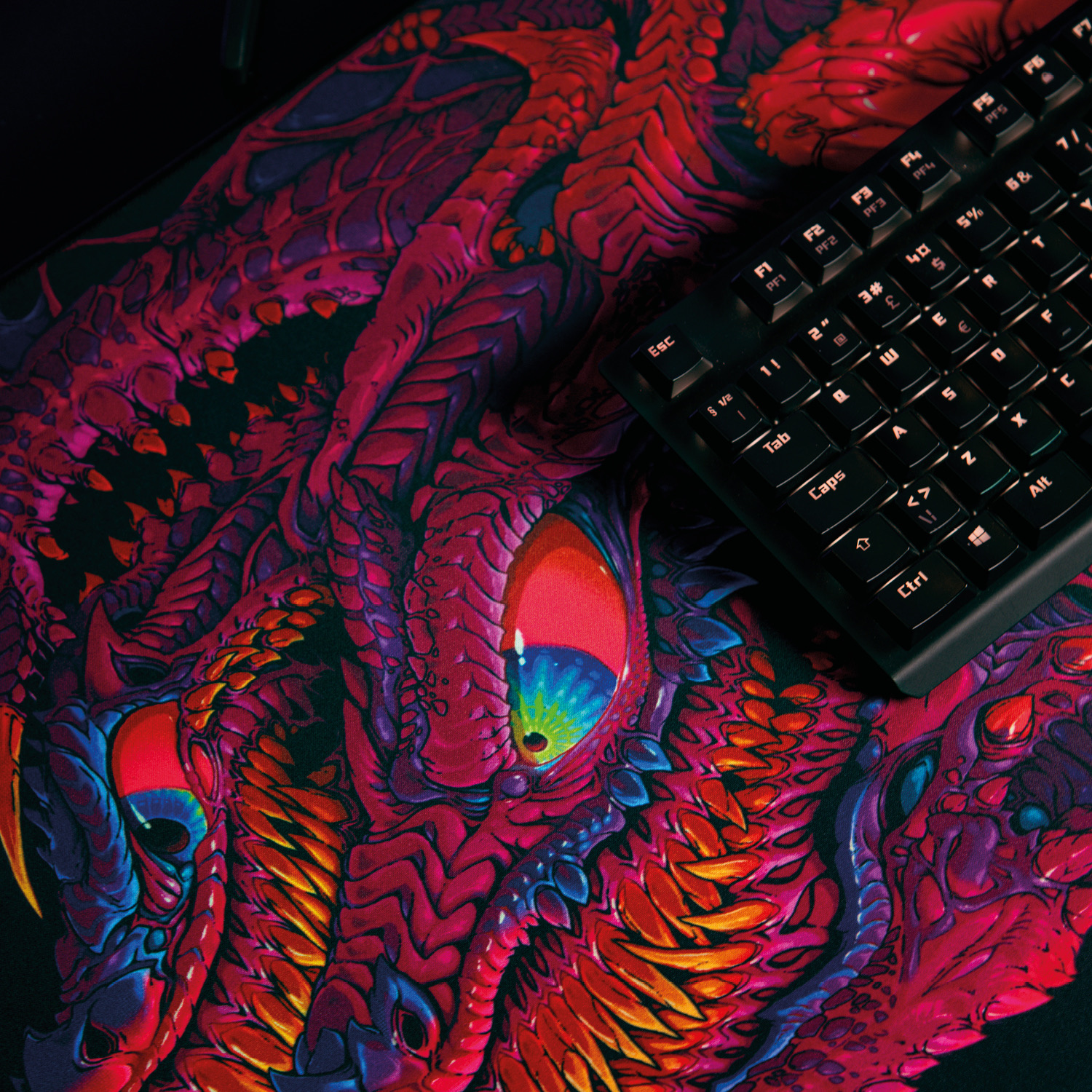 Nahaufnahme eines roten Drachenkopfes auf einem Mauspad neben einer Tastatur.