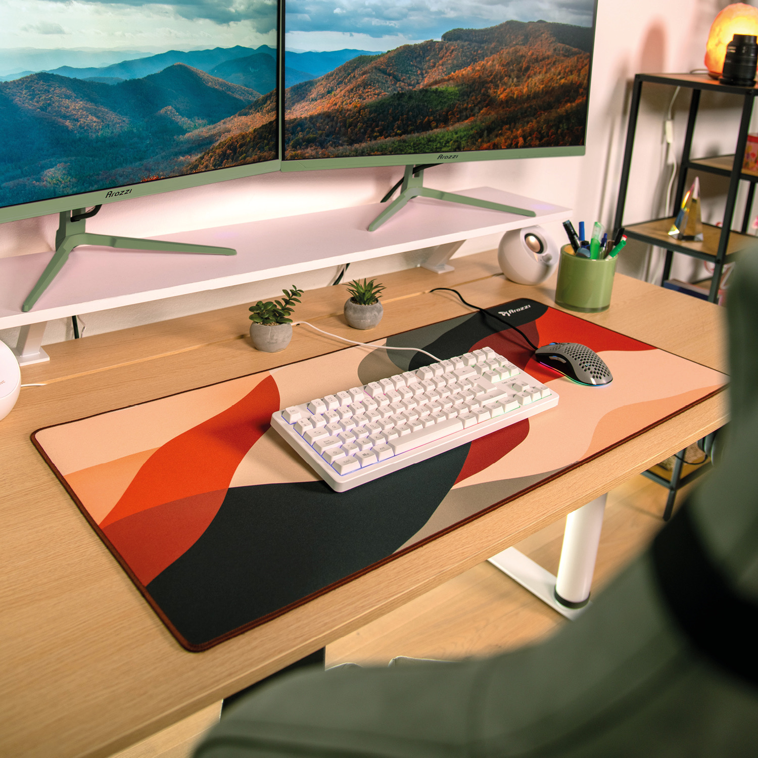 Ein Schreibtisch mit zwei Monitoren, Tastatur, Maus und einer farbigen Unterlage.