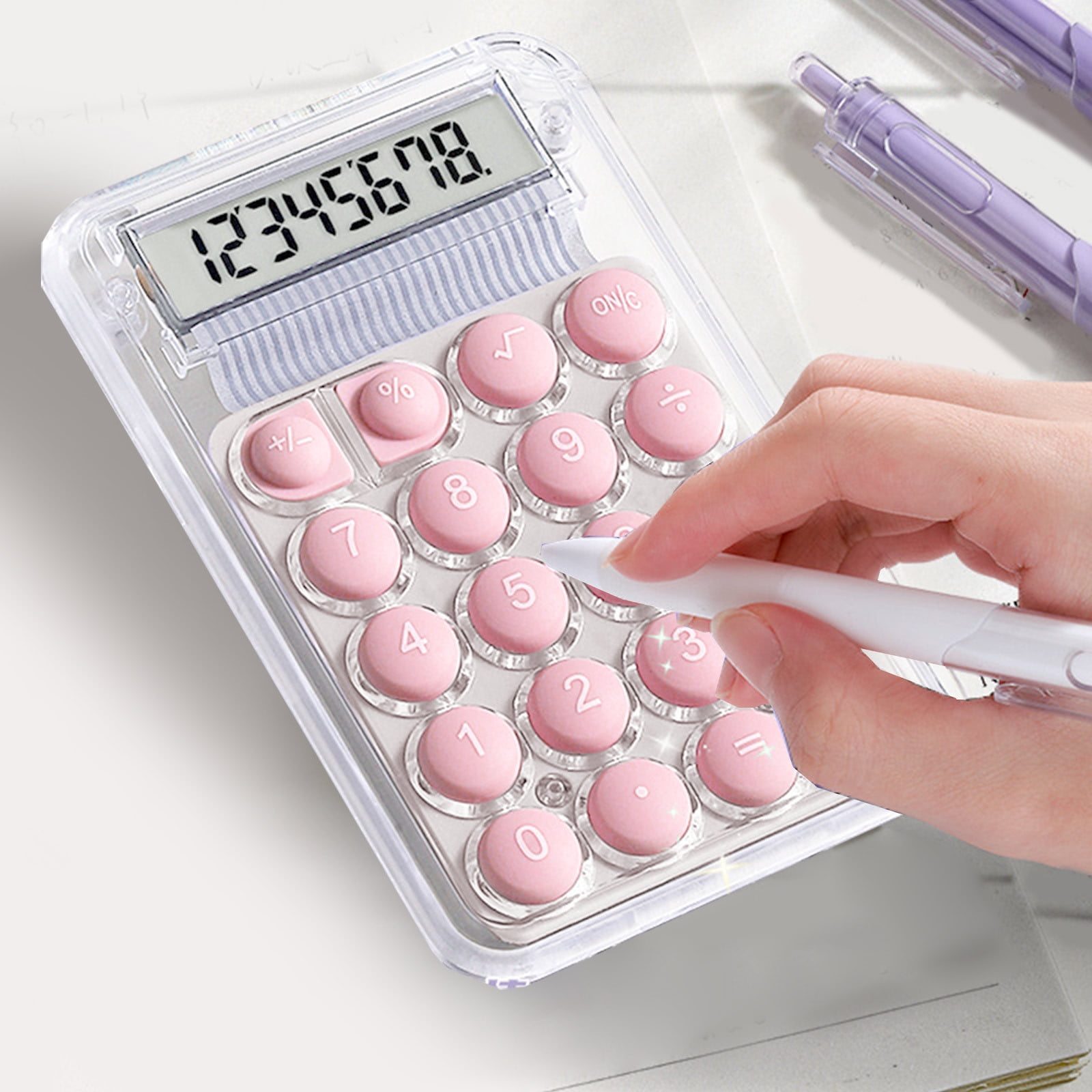 Ein transparenter Taschenrechner mit rosa Knöpfen wird von einer Hand mit einem weißen Stift bedient.