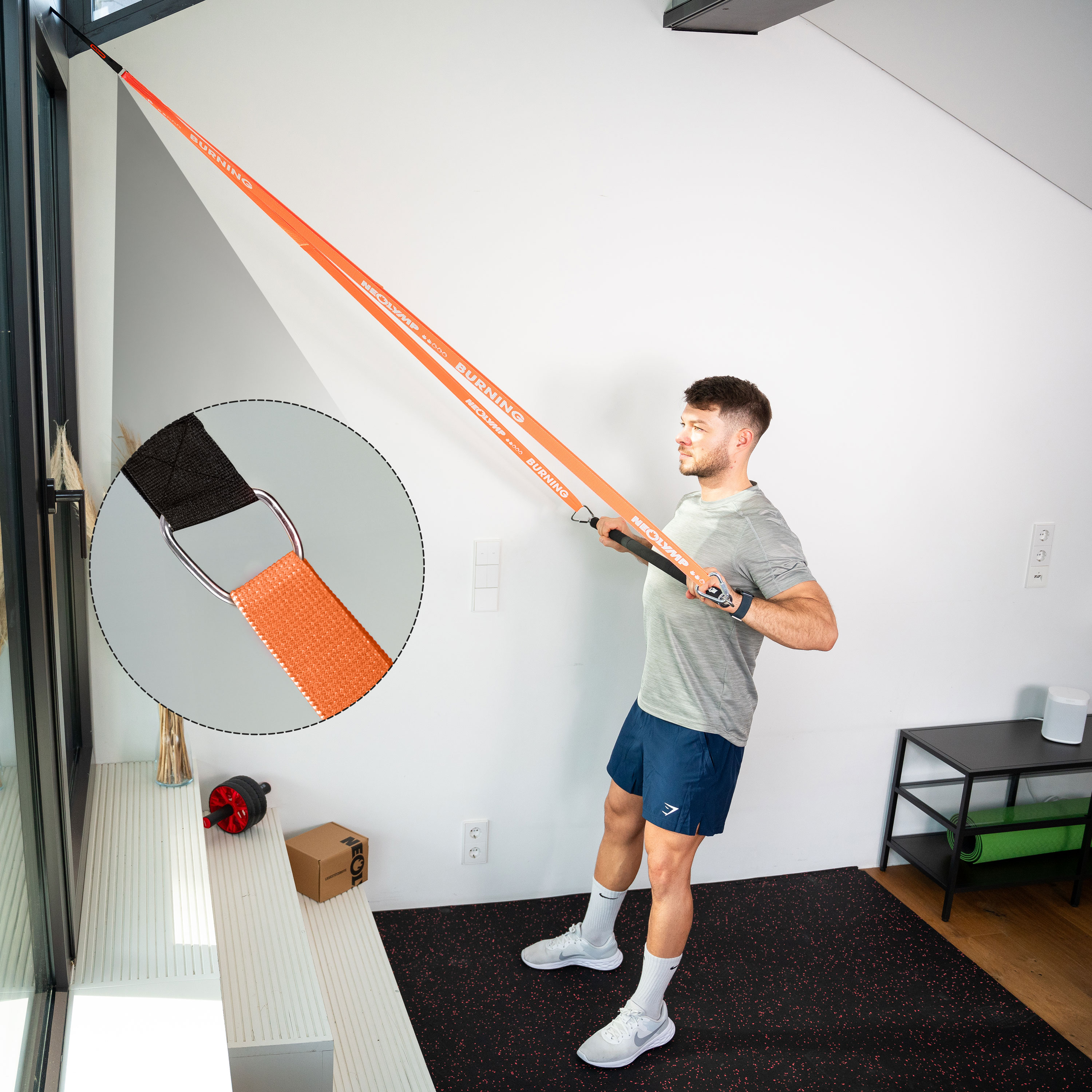 Mann trainiert mit orangefarbenem Widerstandsband, das an einem Fenster befestigt ist.