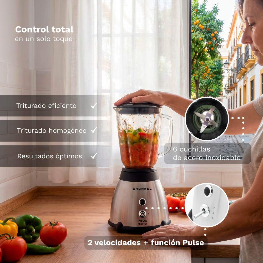 Una licuadora plateada con verduras se asienta sobre una superficie de madera. Una mujer toca la tapa.