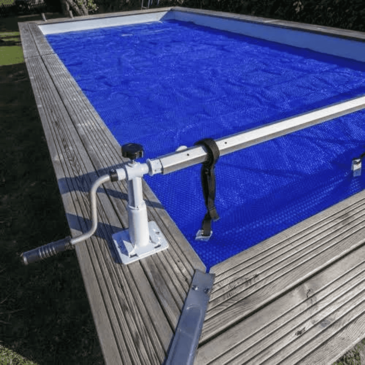 Una cubierta de piscina azul con enrollador en una cubierta de madera.