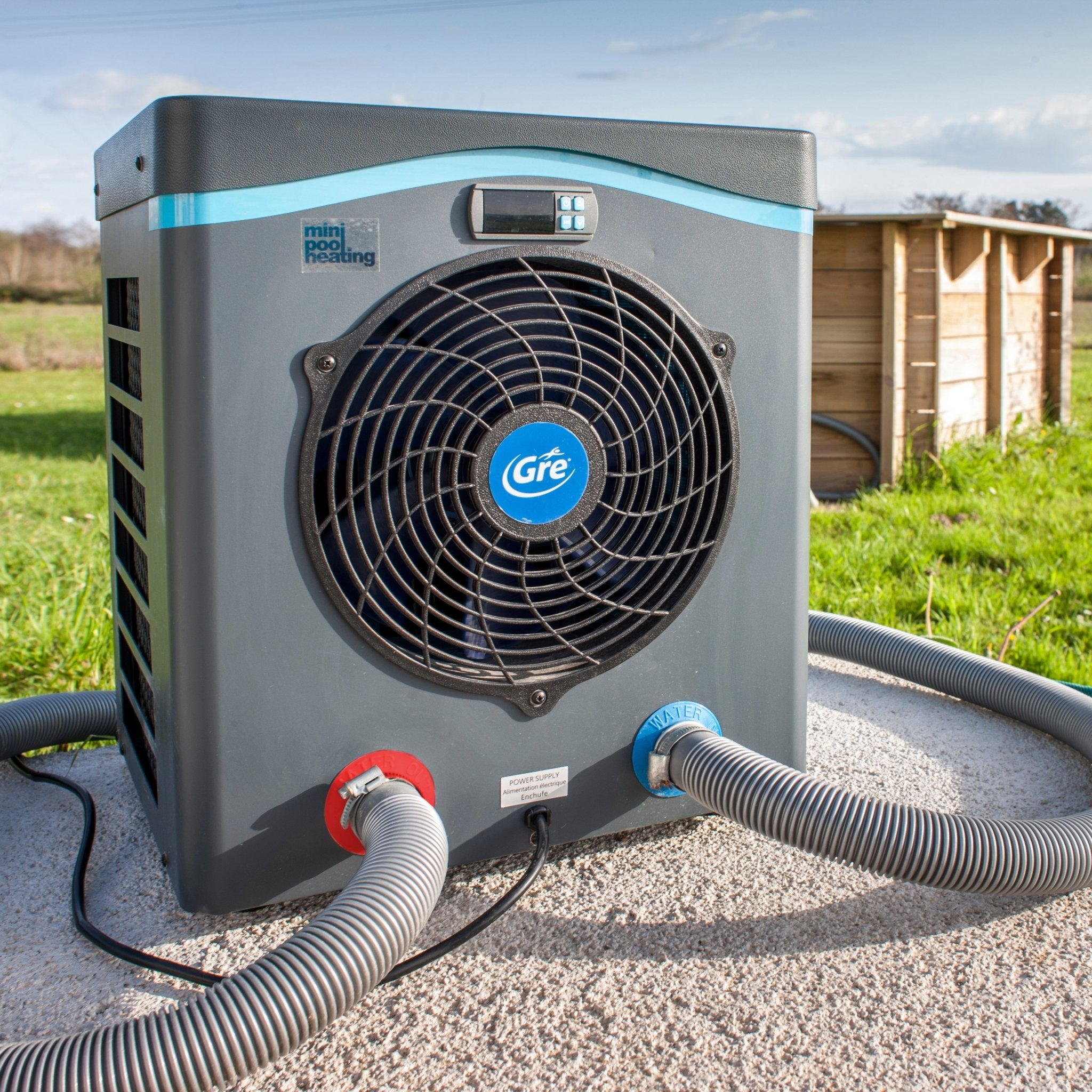 Un calentador de piscina gris con ventilador, mangueras y pantalla digital al aire libre.