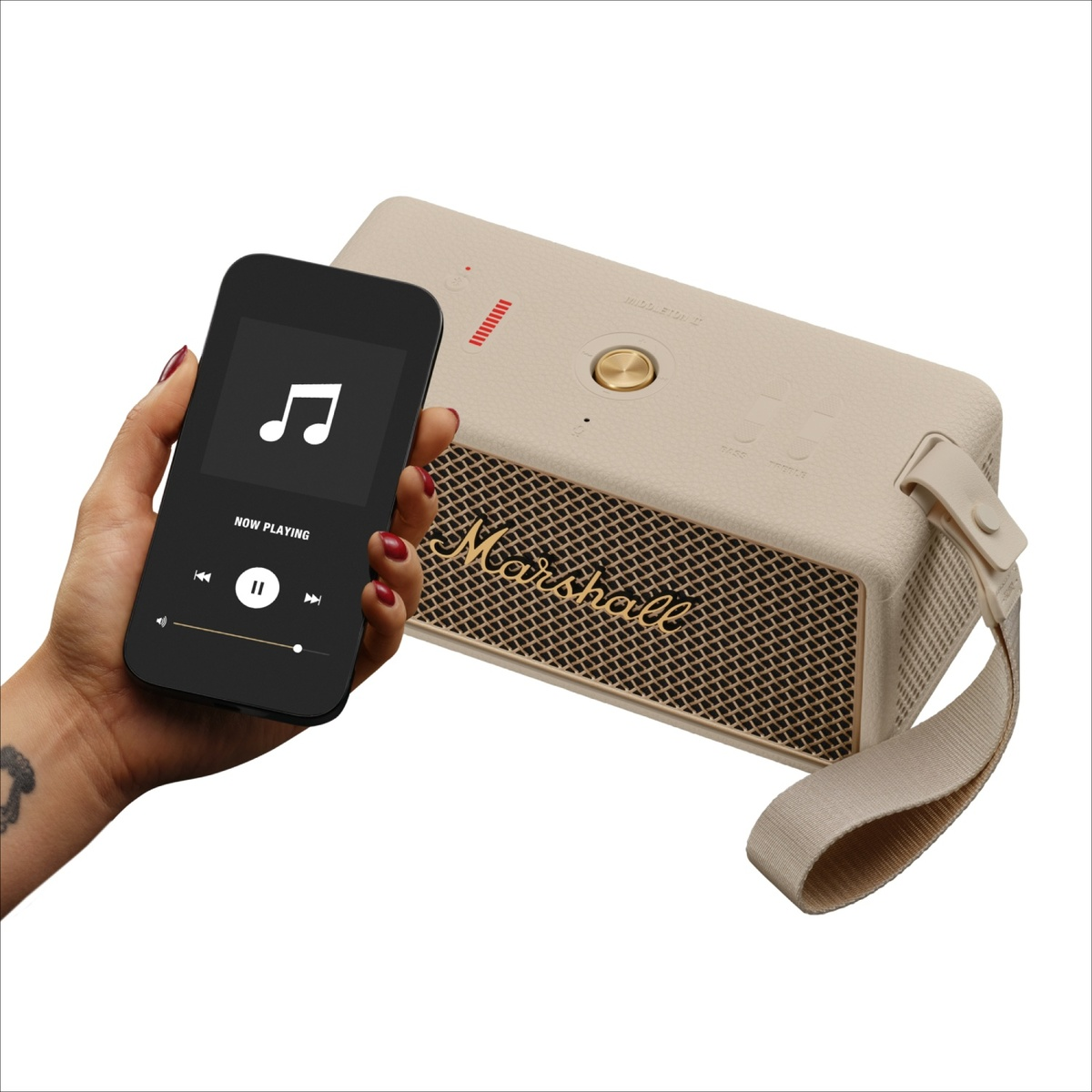 Eine Hand hält ein Smartphone mit Musik-App neben einem beigefarbenen Marshall-Lautsprecher.