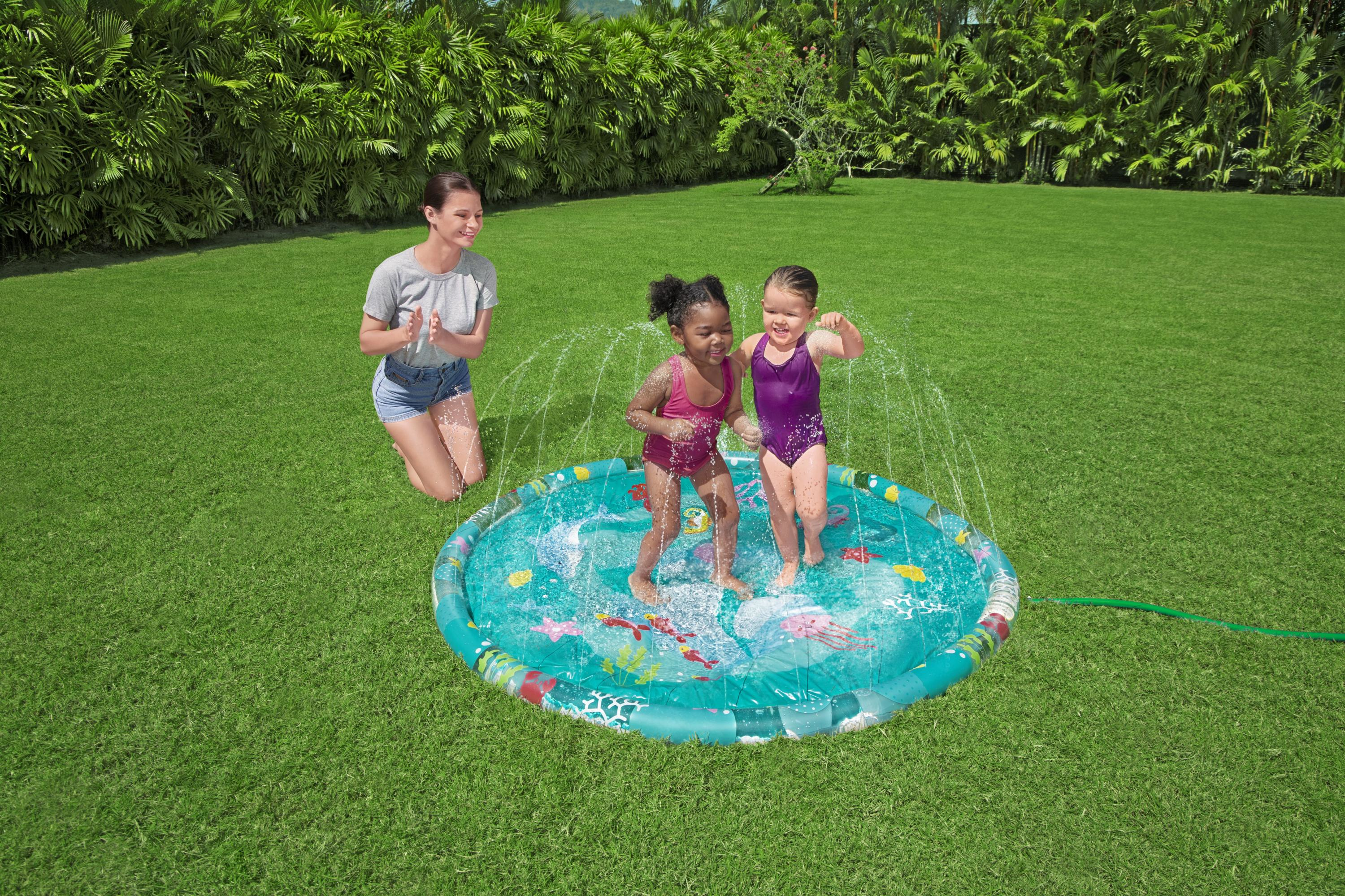 Dos niñas chapotean en una piscina inflable, una mujer observa.