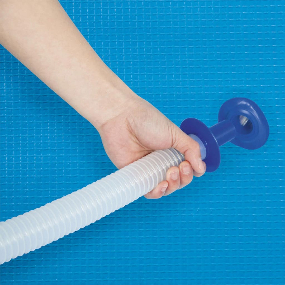 Una mano sujeta un tubo flexible con un mango azul sobre un fondo azul texturizado.