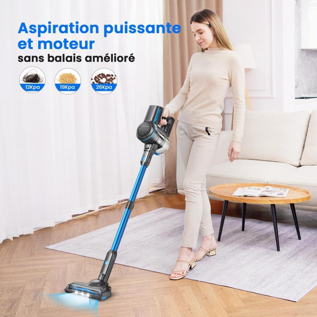 Eine Frau benutzt einen blauen Handstaubsauger in einem Wohnzimmer auf einem Teppich.