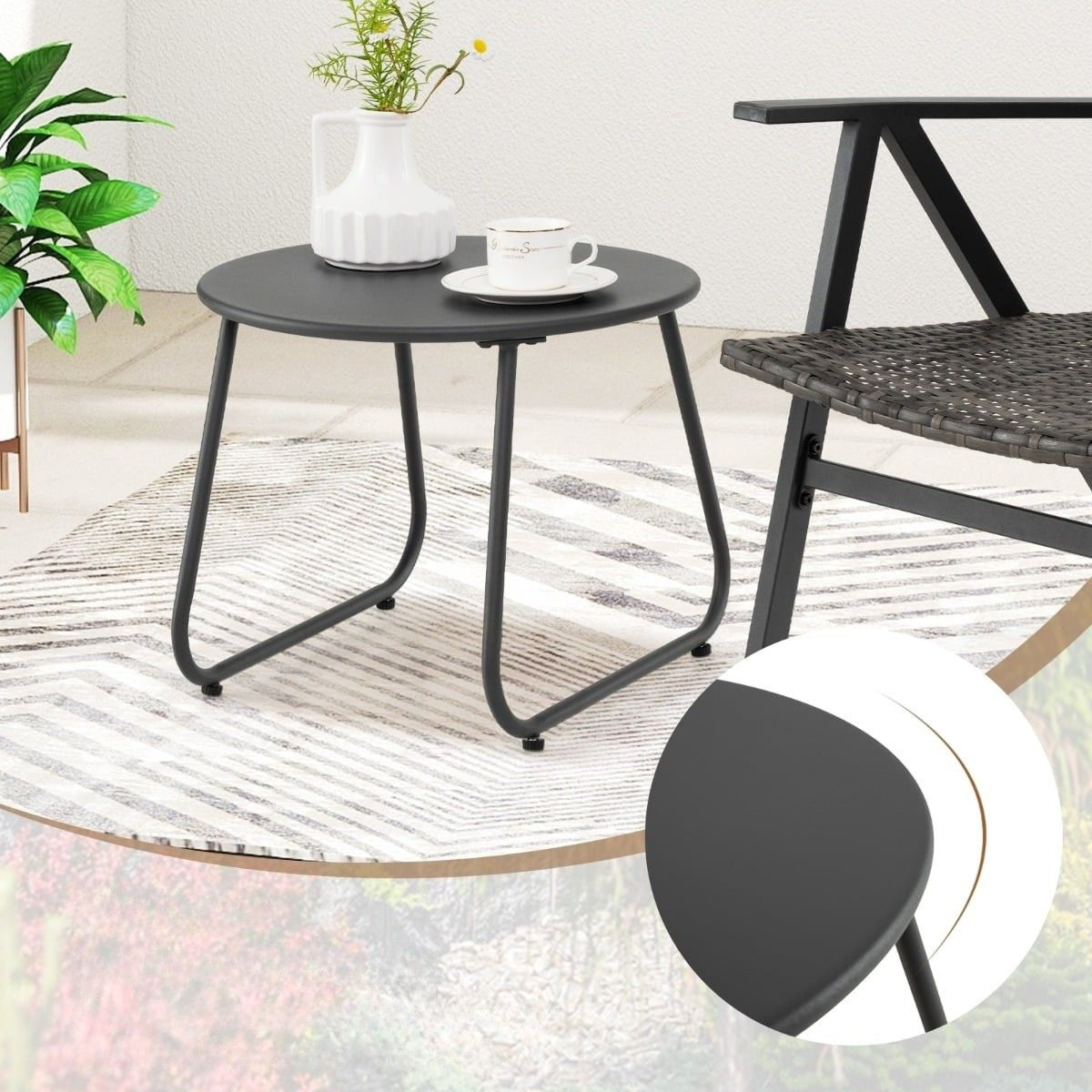 Een zwarte ronde tafel met vaas en kopje staat op een kleed.