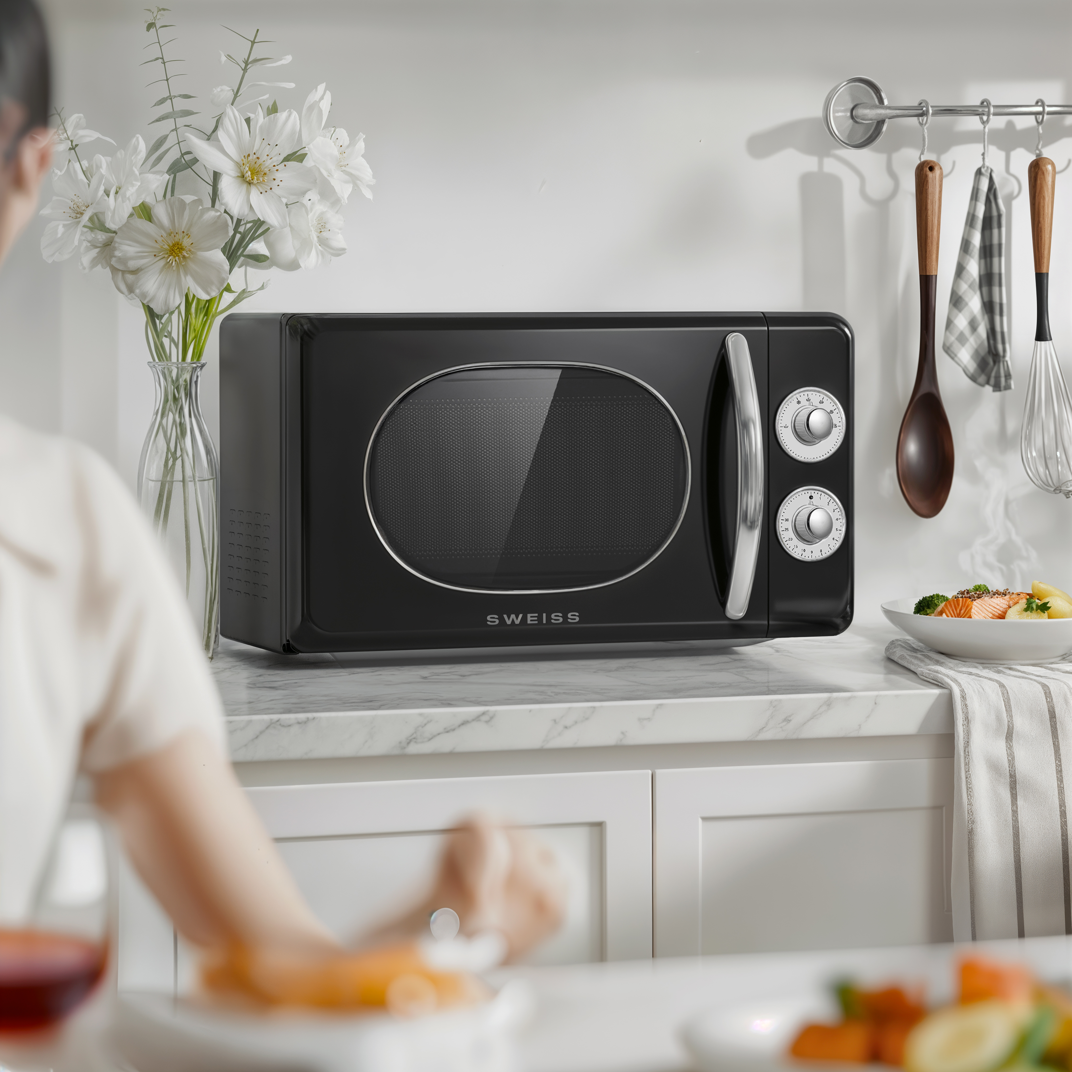 Microondas retro negro con flores blancas y comida en la encimera.