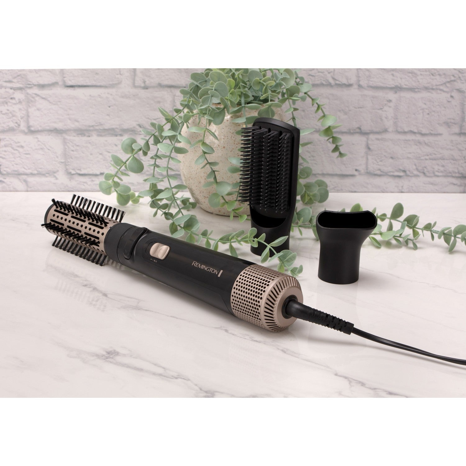 A black Remington hair dryer with attachments and plants on marble.