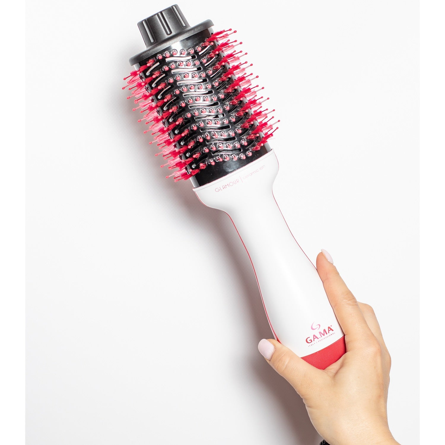 A hand holds a white and red hairdryer with a black brush head.
