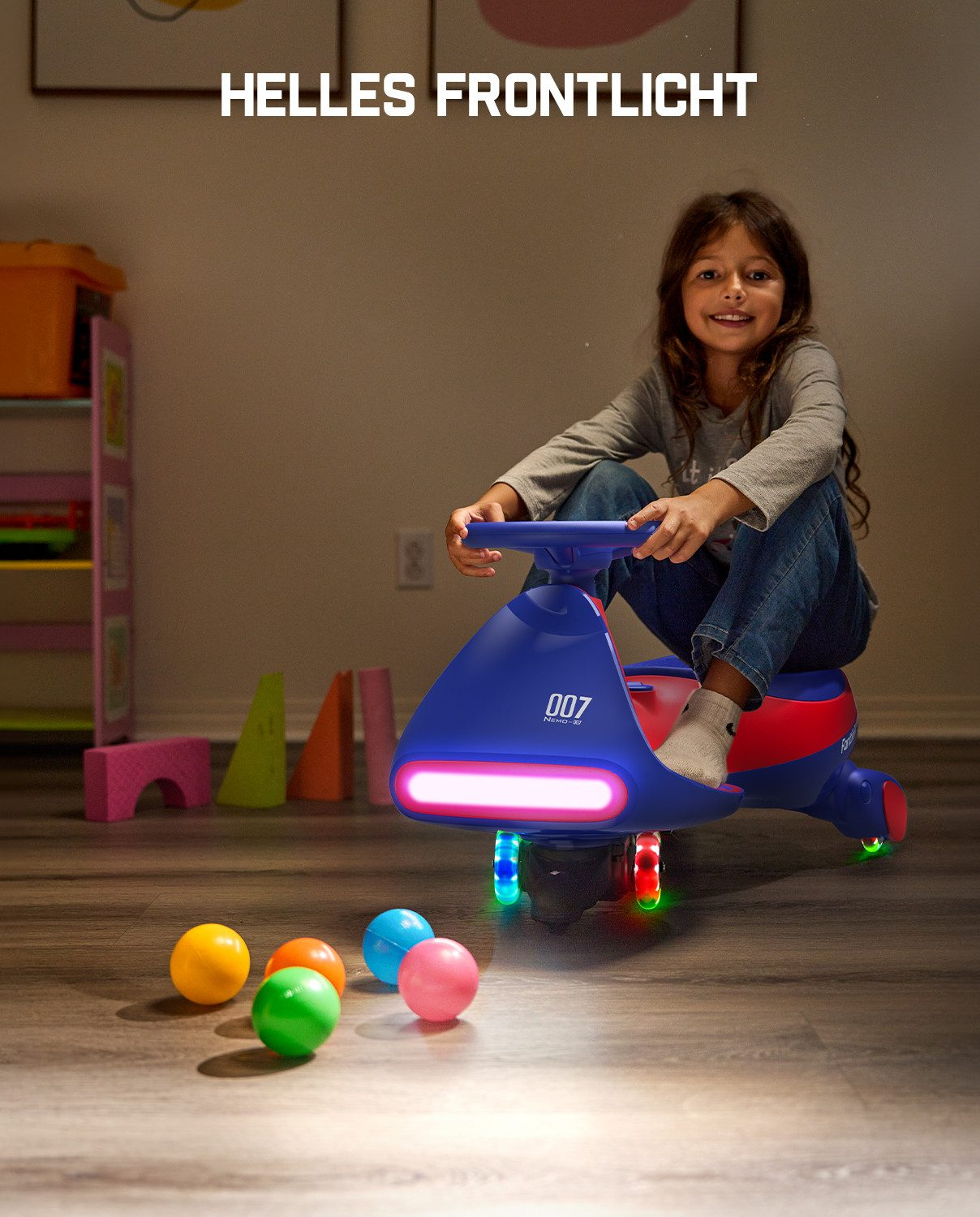 Ein Mädchen fährt ein blaues Spielzeugauto mit Lichtern. Mehrere Bälle liegen auf dem Boden.