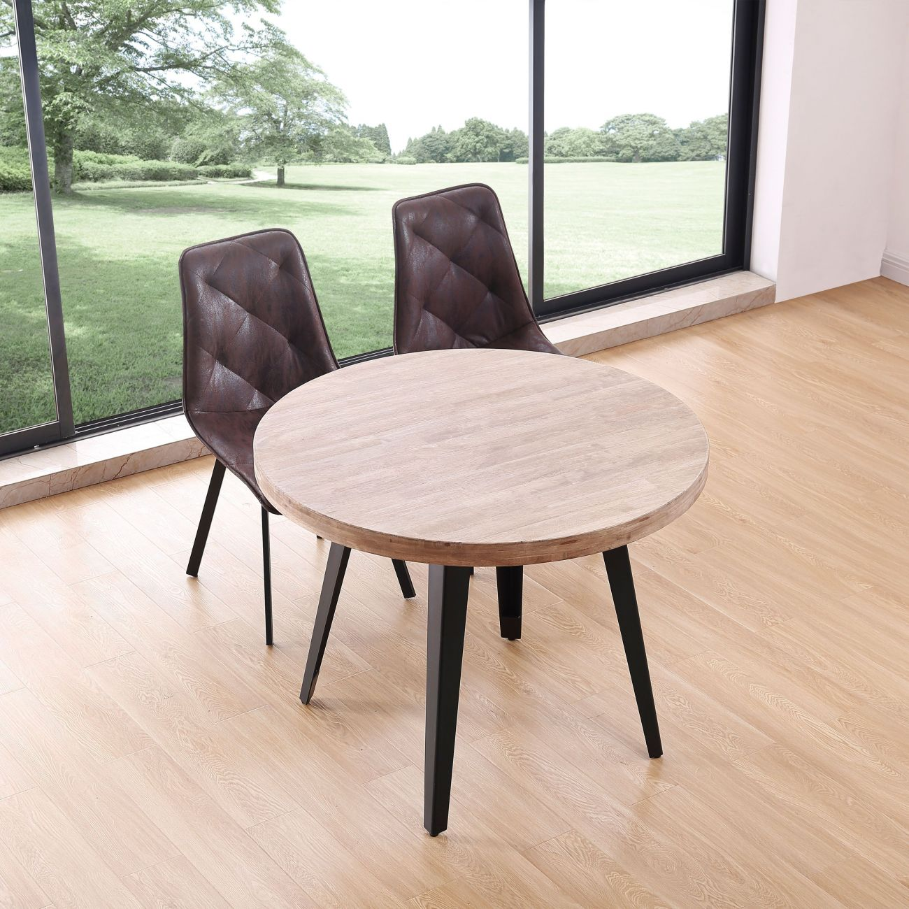 Una mesa redonda de madera con dos sillas de cuero marrón frente a una ventana grande.