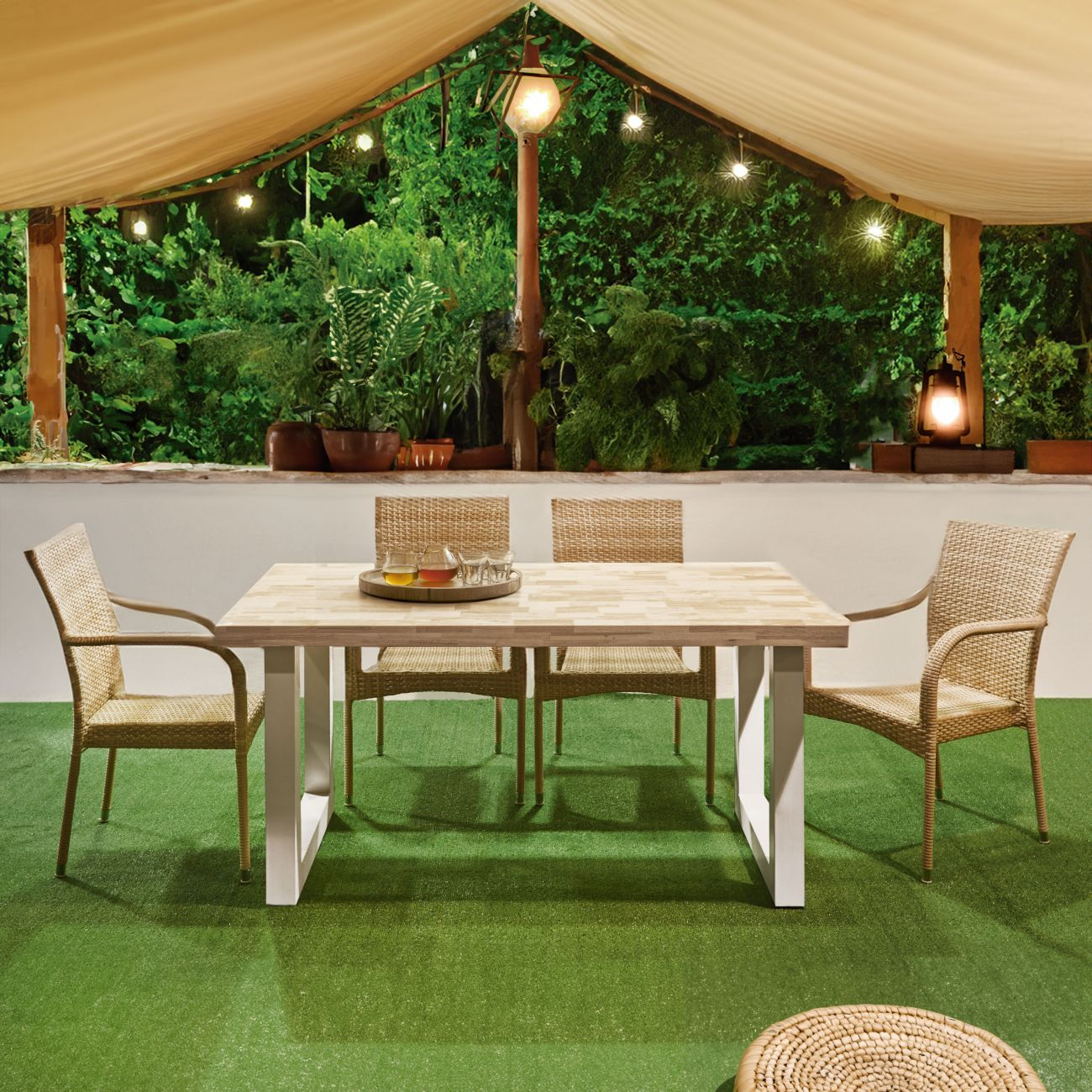 Un juego de comedor exterior con sillas de mimbre y mesa de madera sobre césped artificial.