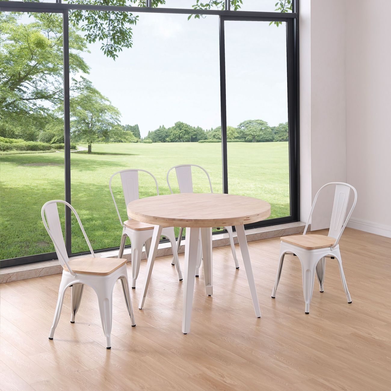 Una mesa redonda de madera con cuatro sillas blancas frente a una gran ventana con vistas a un jardín.