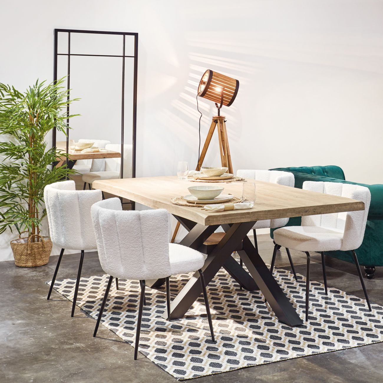 Una mesa de comedor con sillas blancas, espejo, lámpara y planta.
