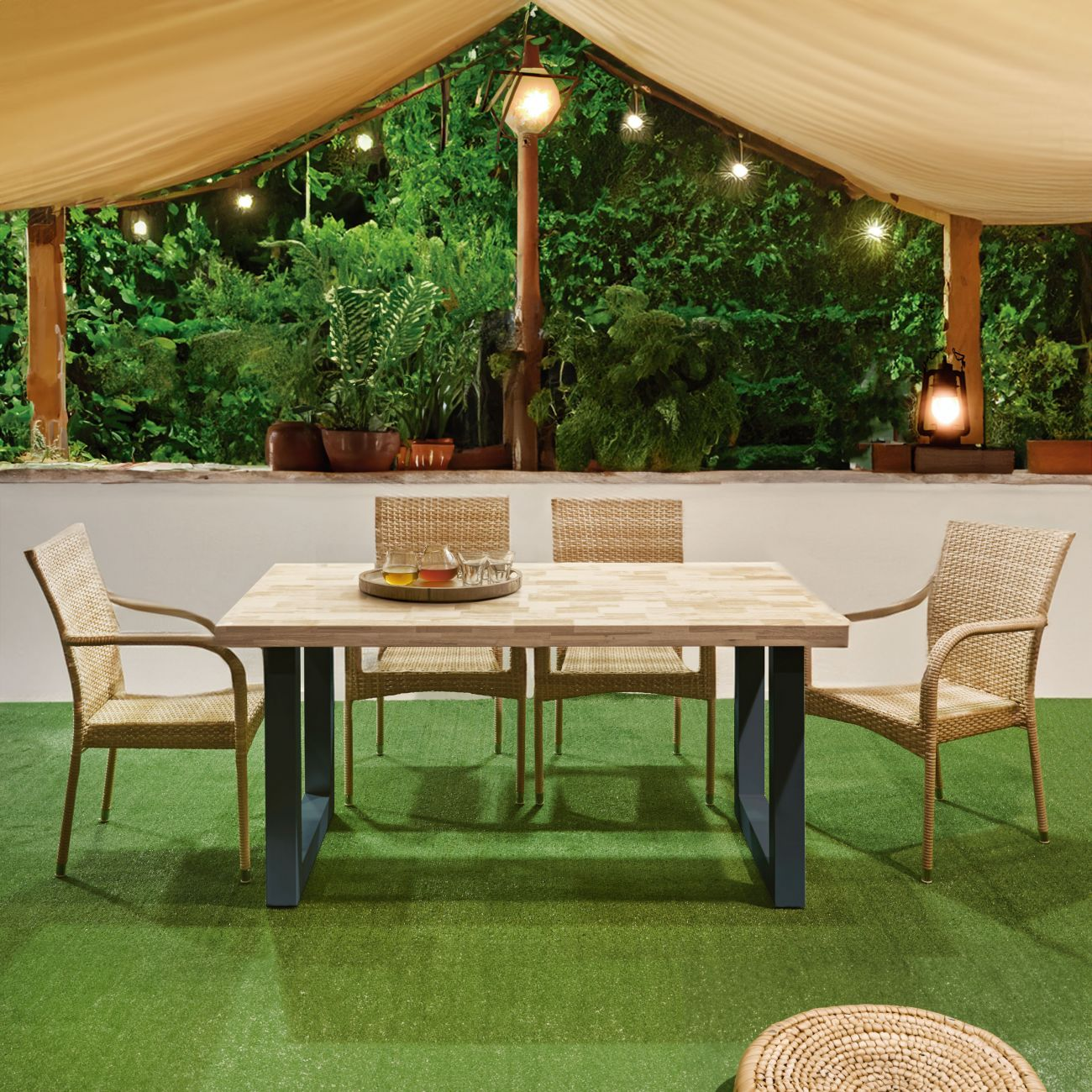Una mesa de jardín de madera con cuatro sillas de ratán sobre césped artificial.