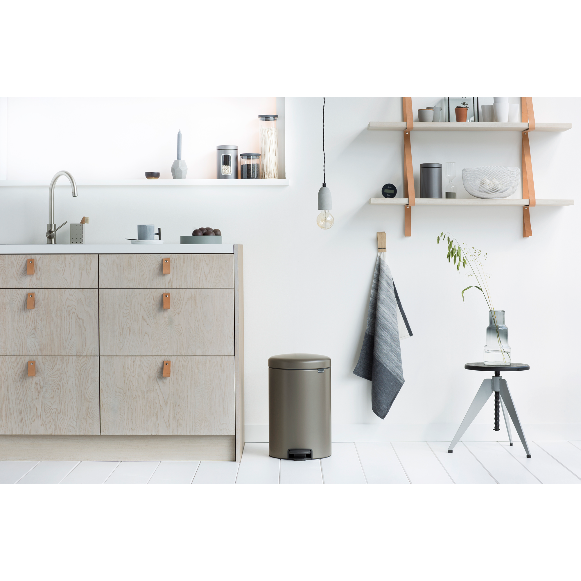 Moderne keuken met lichte houten kasten, gootsteen, prullenbak en planken.