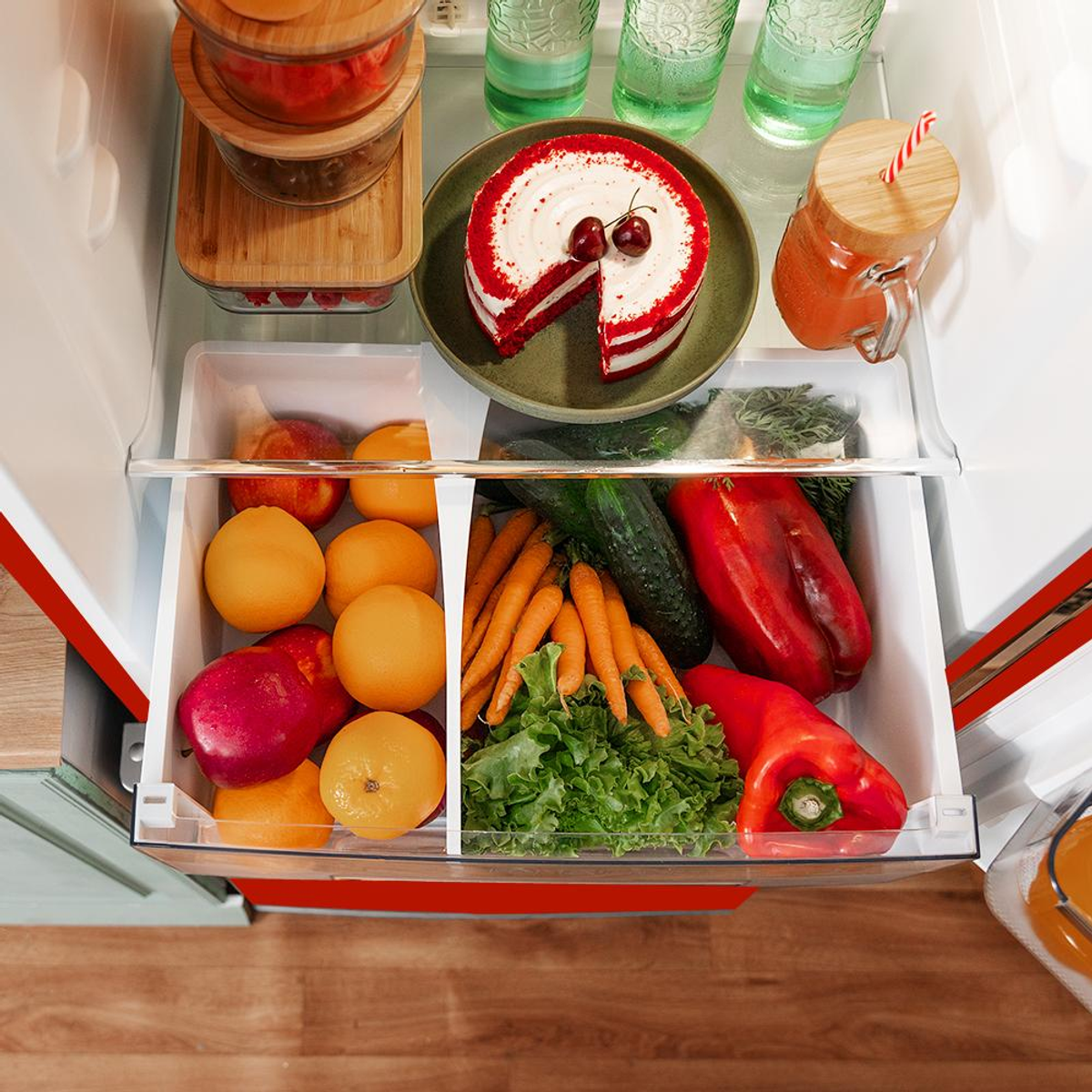 Un refrigerador abierto con frutas, verduras, pastel y bebidas.