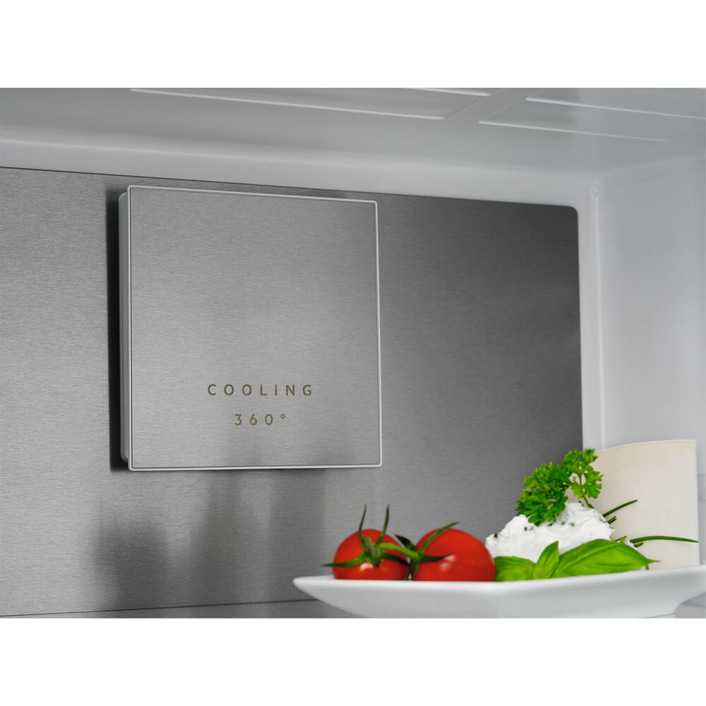 Pannello argentato con scritta "COOLING 360°". Pomodori freschi ed erbe su piatto bianco.