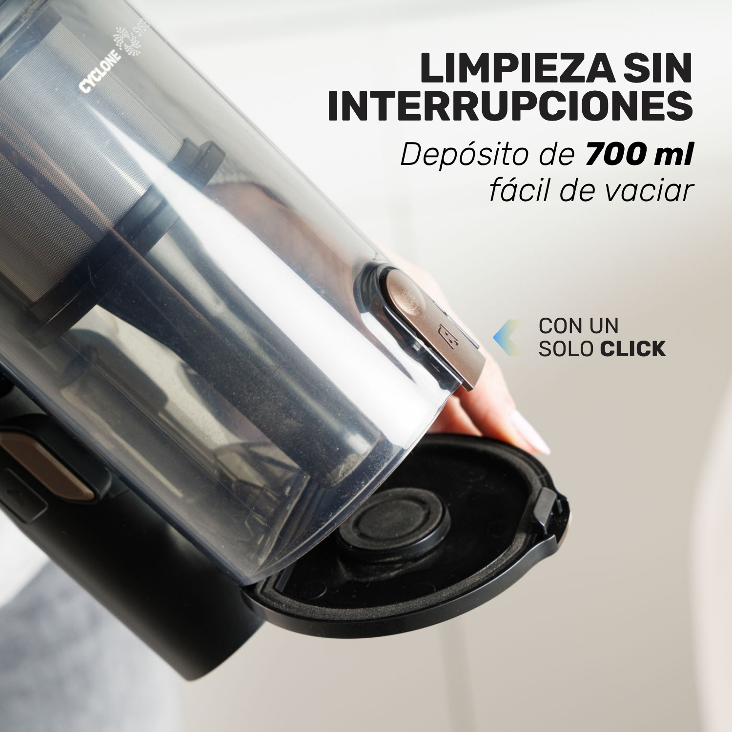 Una mano vacía el depósito de una aspiradora de 700 ml.