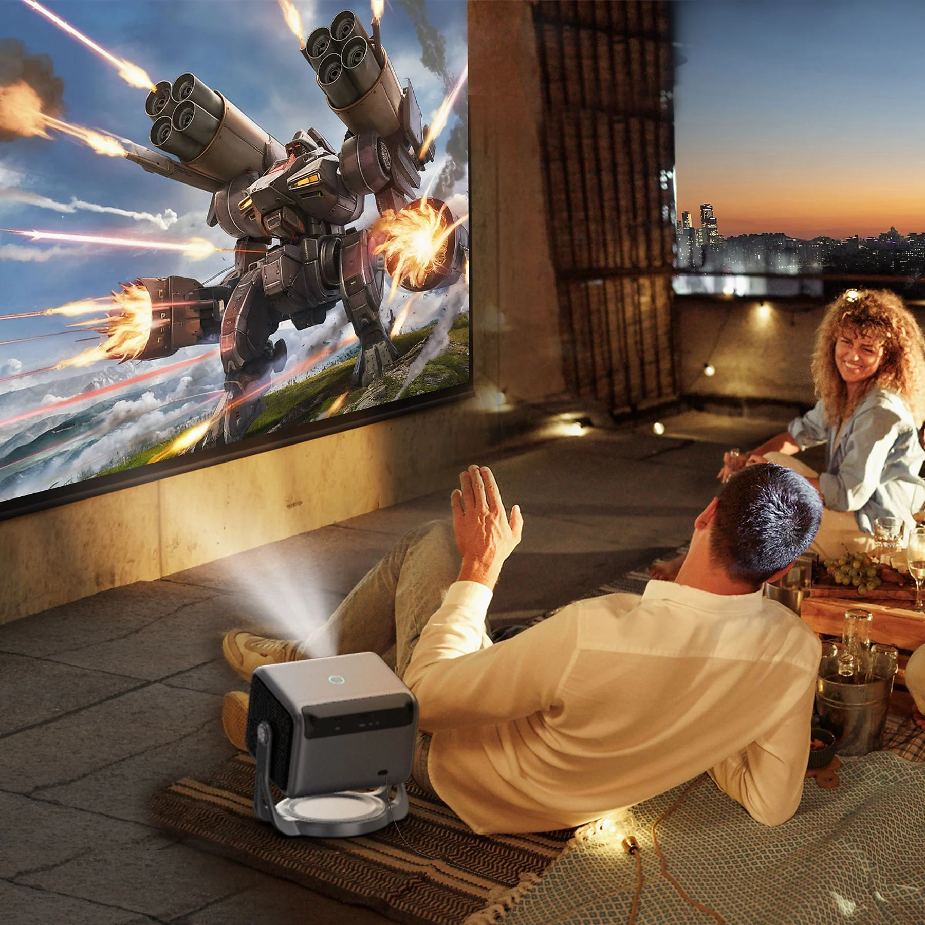 Ein Mann und eine Frau genießen einen Film auf einer Leinwand auf einer Dachterrasse bei Sonnenuntergang.