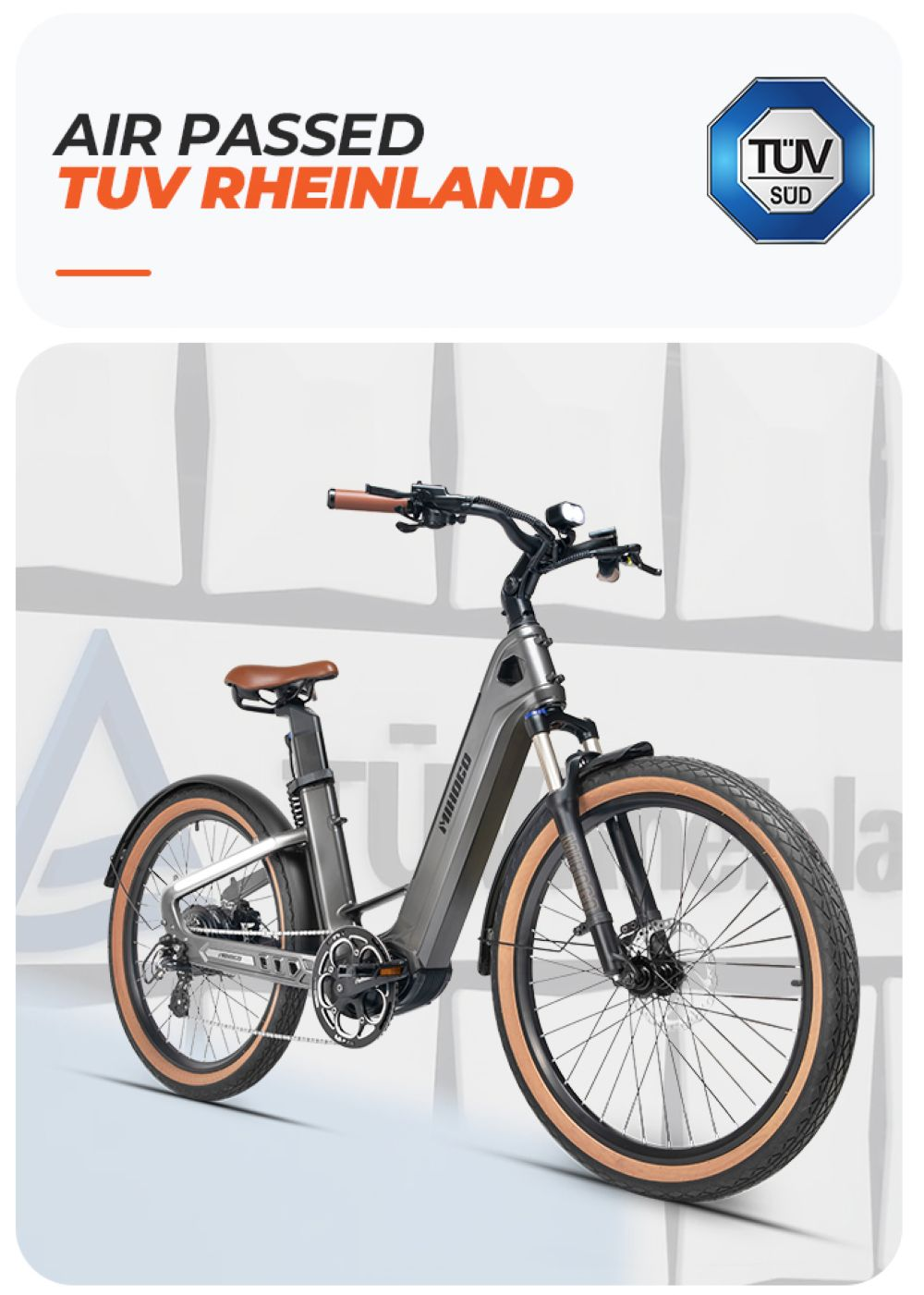 Bicicleta eléctrica gris con asiento y puños marrones, llantas anchas y logo TUV SUD.