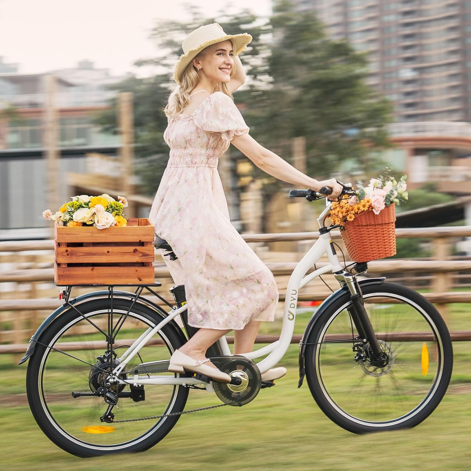 Una mujer con sombrero de paja monta una bicicleta con flores en la cesta y caja de madera.