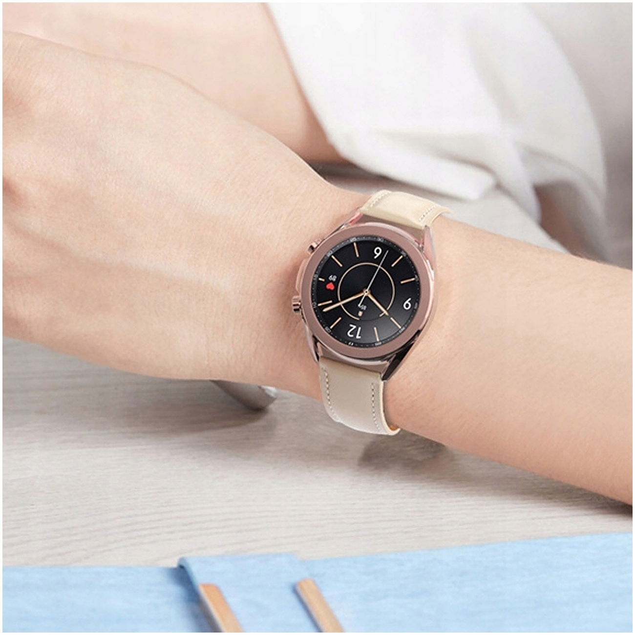 Kobieta nosi na nadgarstku różowo-złoty smartwatch z jasną skórzaną bransoletą.
