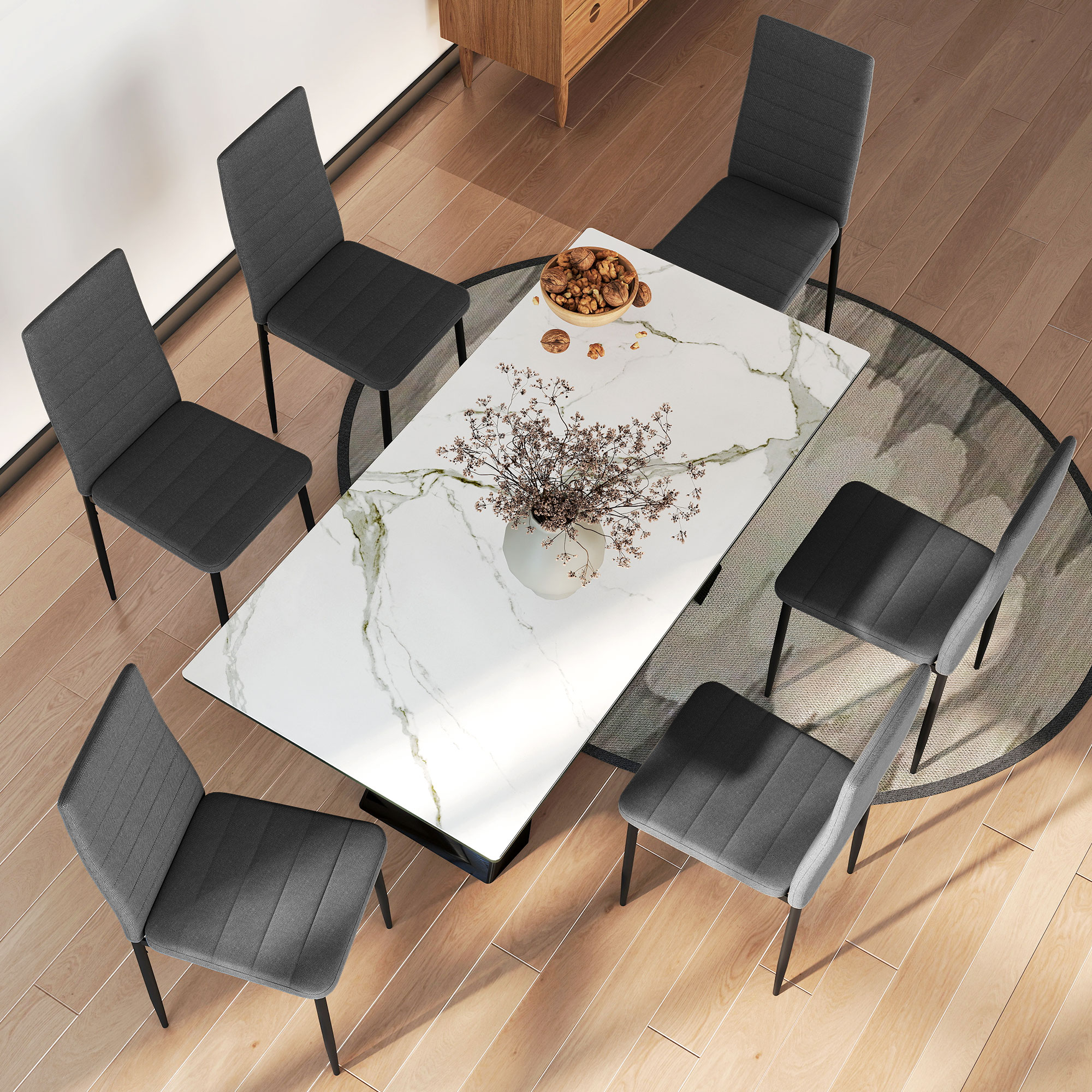 Una mesa de comedor de mármol con seis sillas, un jarrón de flores y un cuenco de nueces.