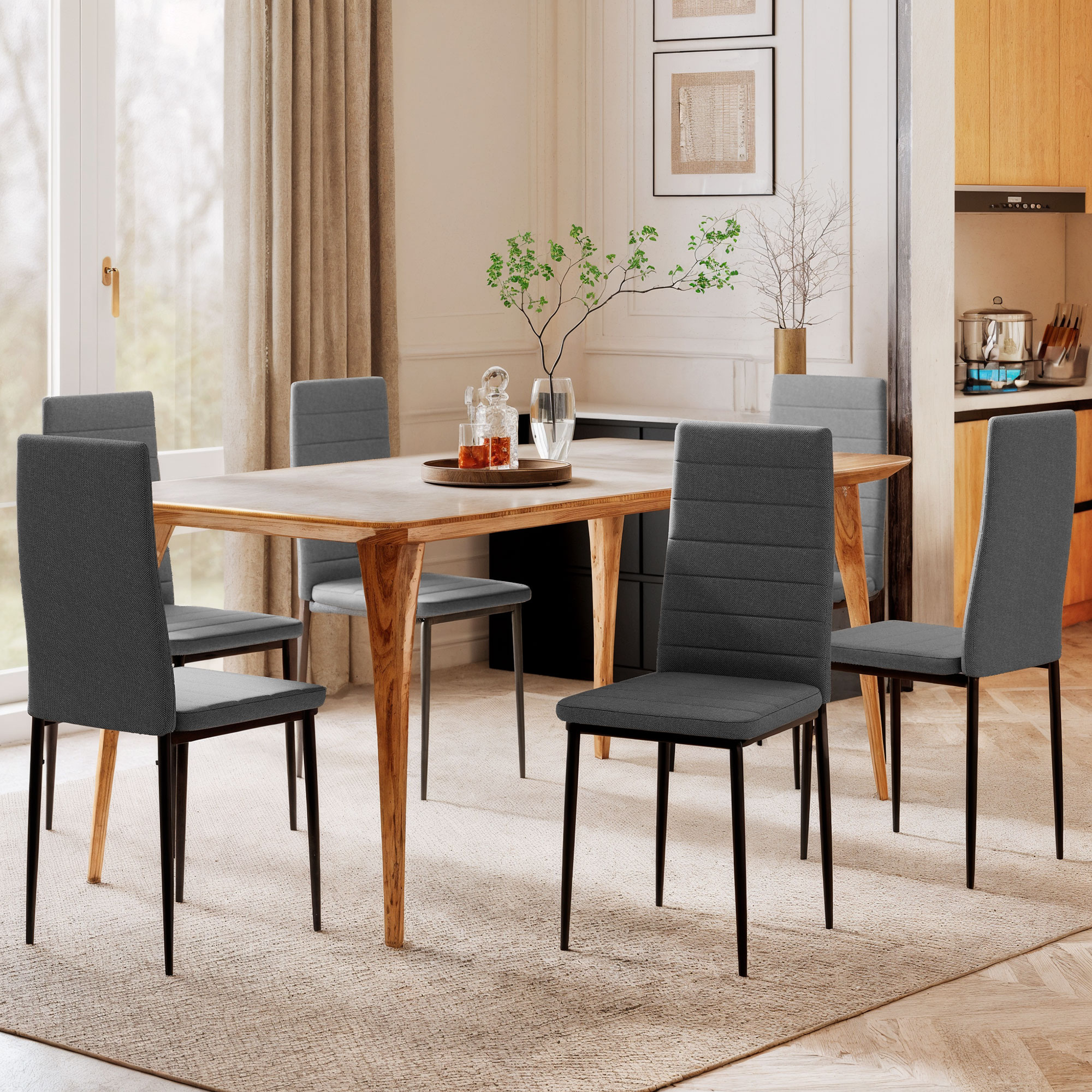 Un comedor con mesa de madera, sillas grises, cortinas y encimera de cocina.