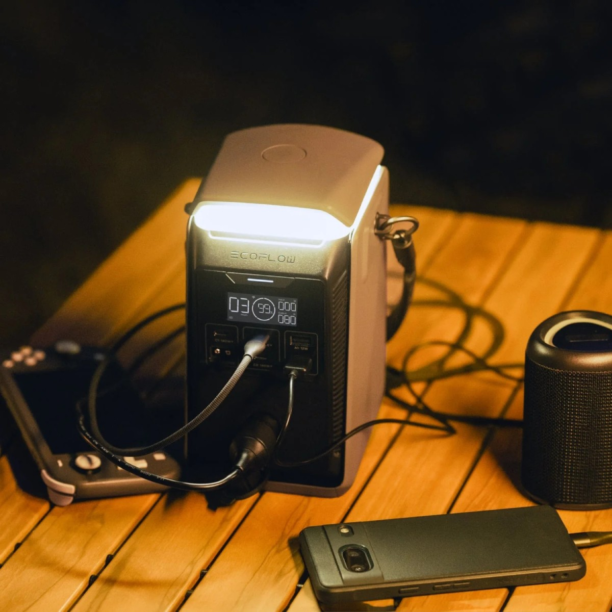 Una centrale elettrica portatile con luce accesa, che carica dispositivi su un tavolo di legno.