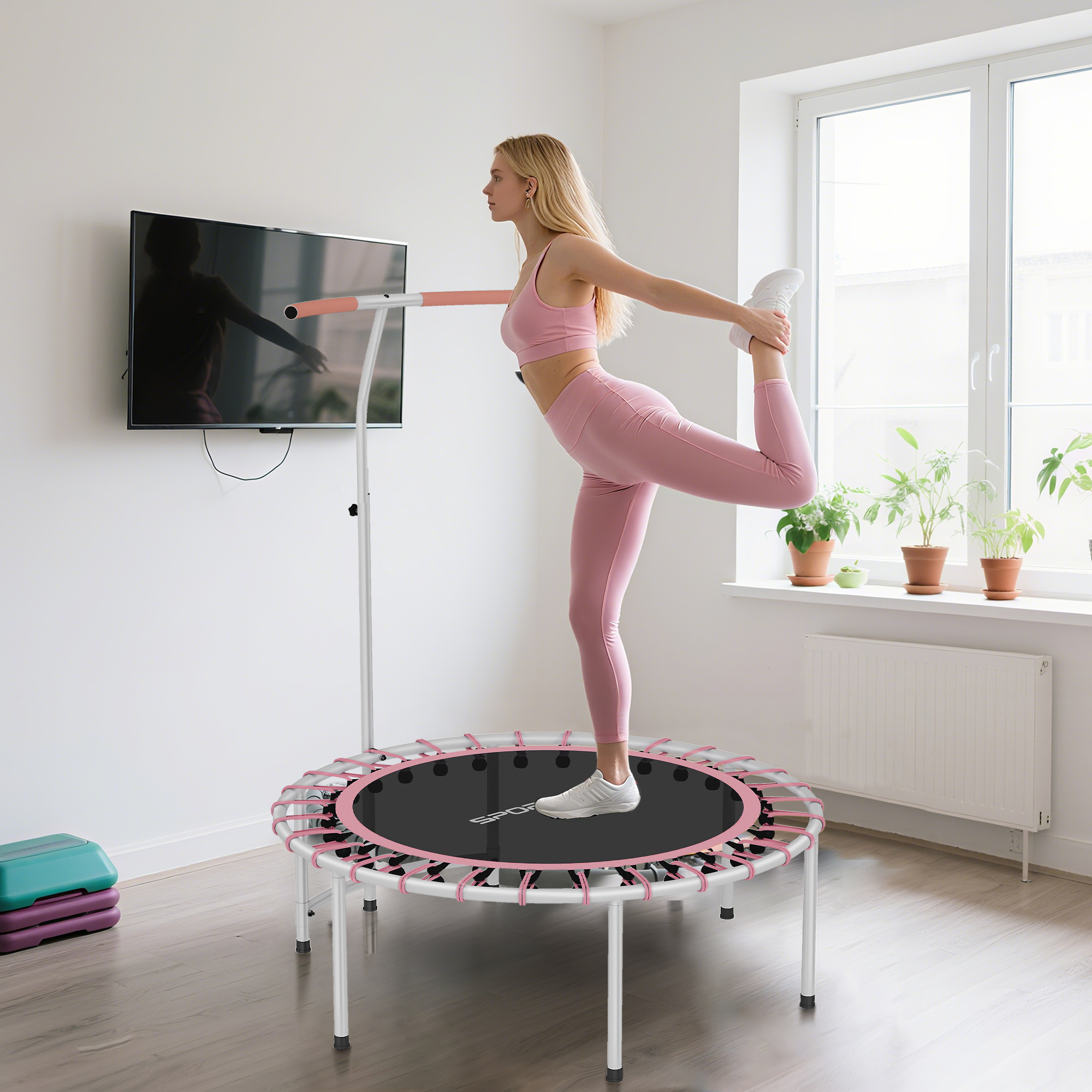 Una mujer con ropa deportiva rosa hace una postura de yoga en un minitrampolín.
