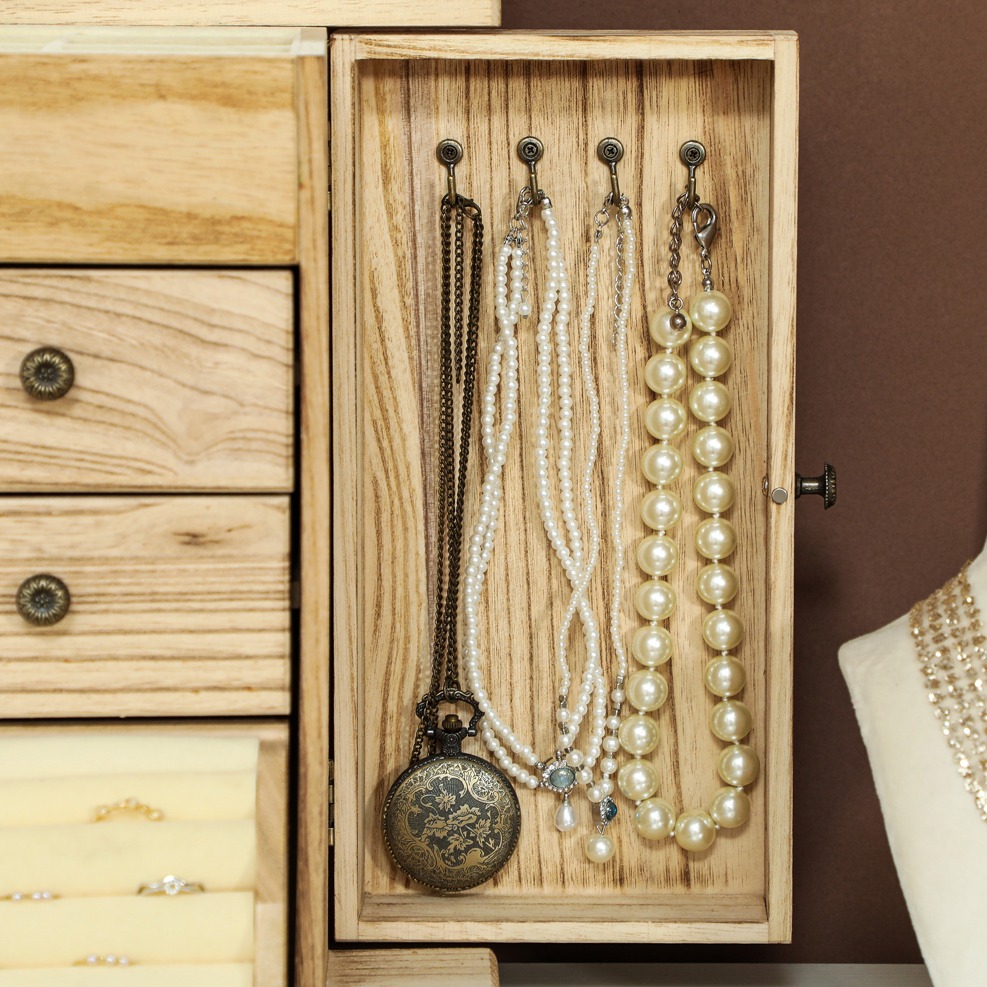 Una caja de joyería de madera con cajones y collares colgantes.