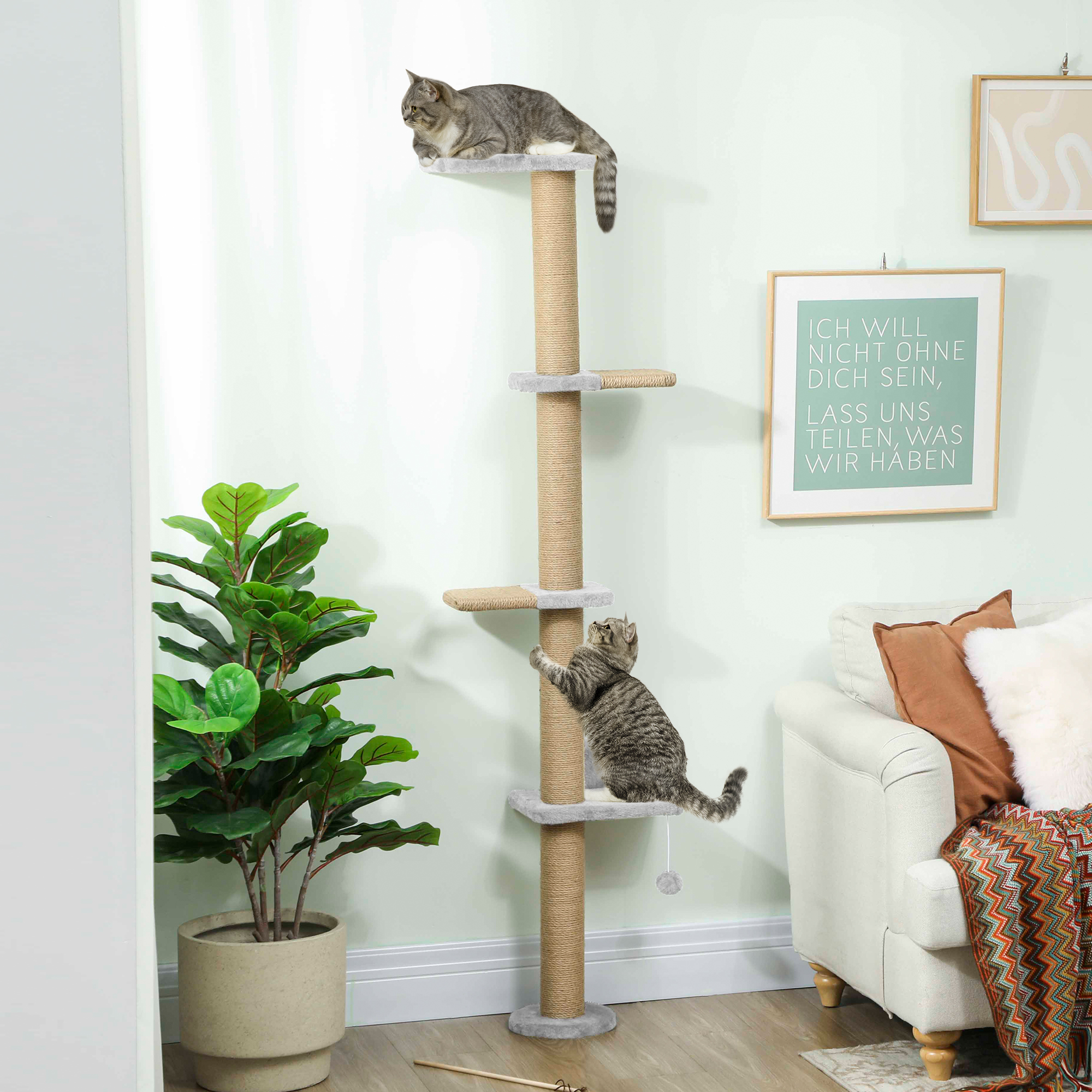 Dos gatos en un árbol rascador, con una planta y un sofá cerca.