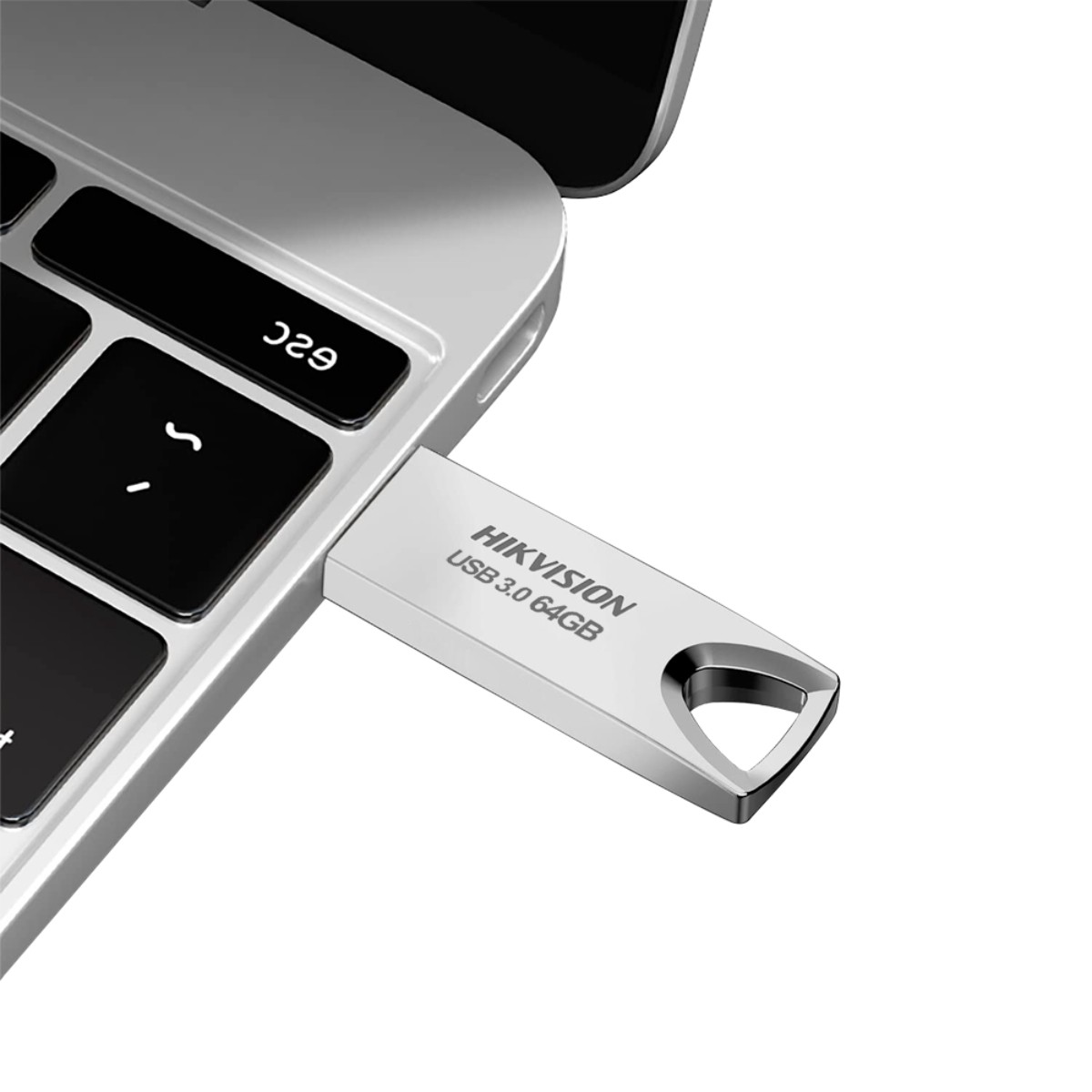 Una chiavetta USB Hikvision argentata USB 3.0 da 64 GB inserita nella tastiera di un laptop.