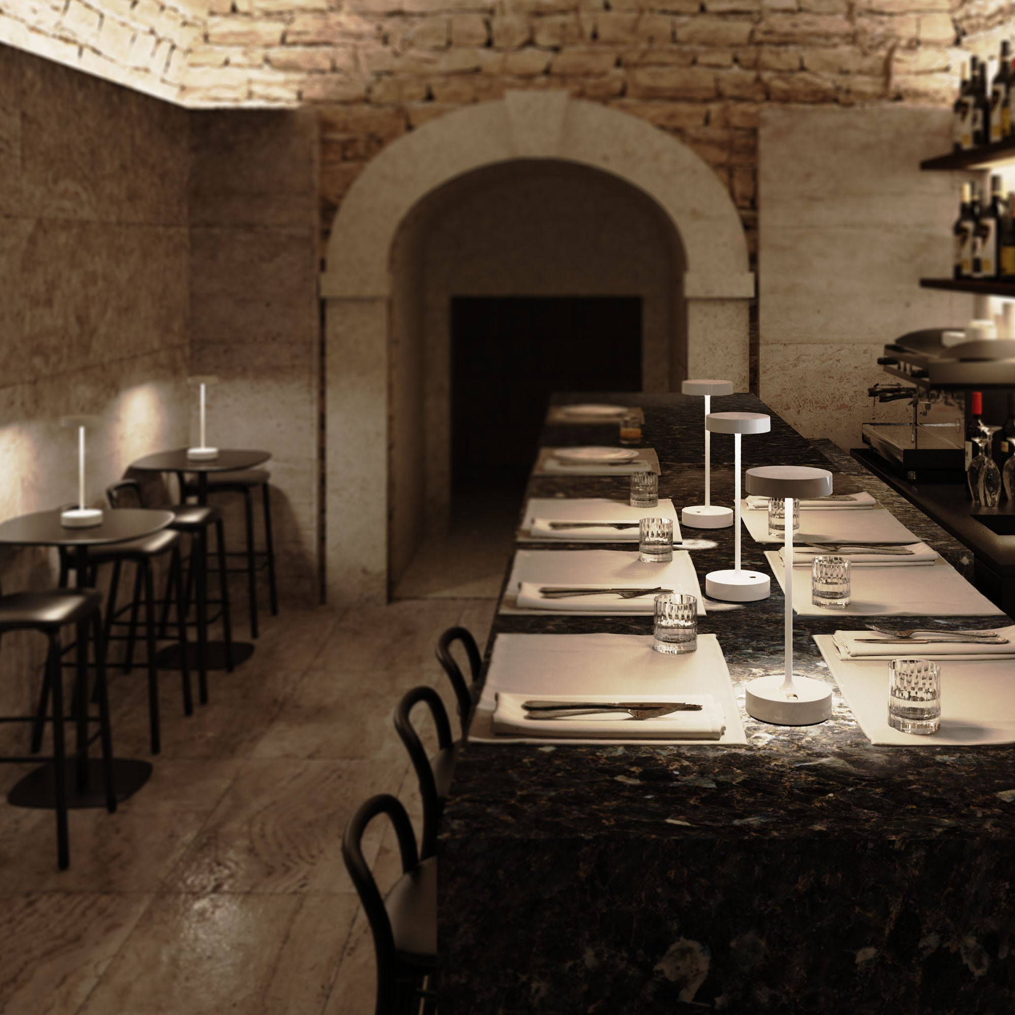 Ein Restaurant mit Bar, Tischen und Stühlen, beleuchtet von kleinen Lampen.