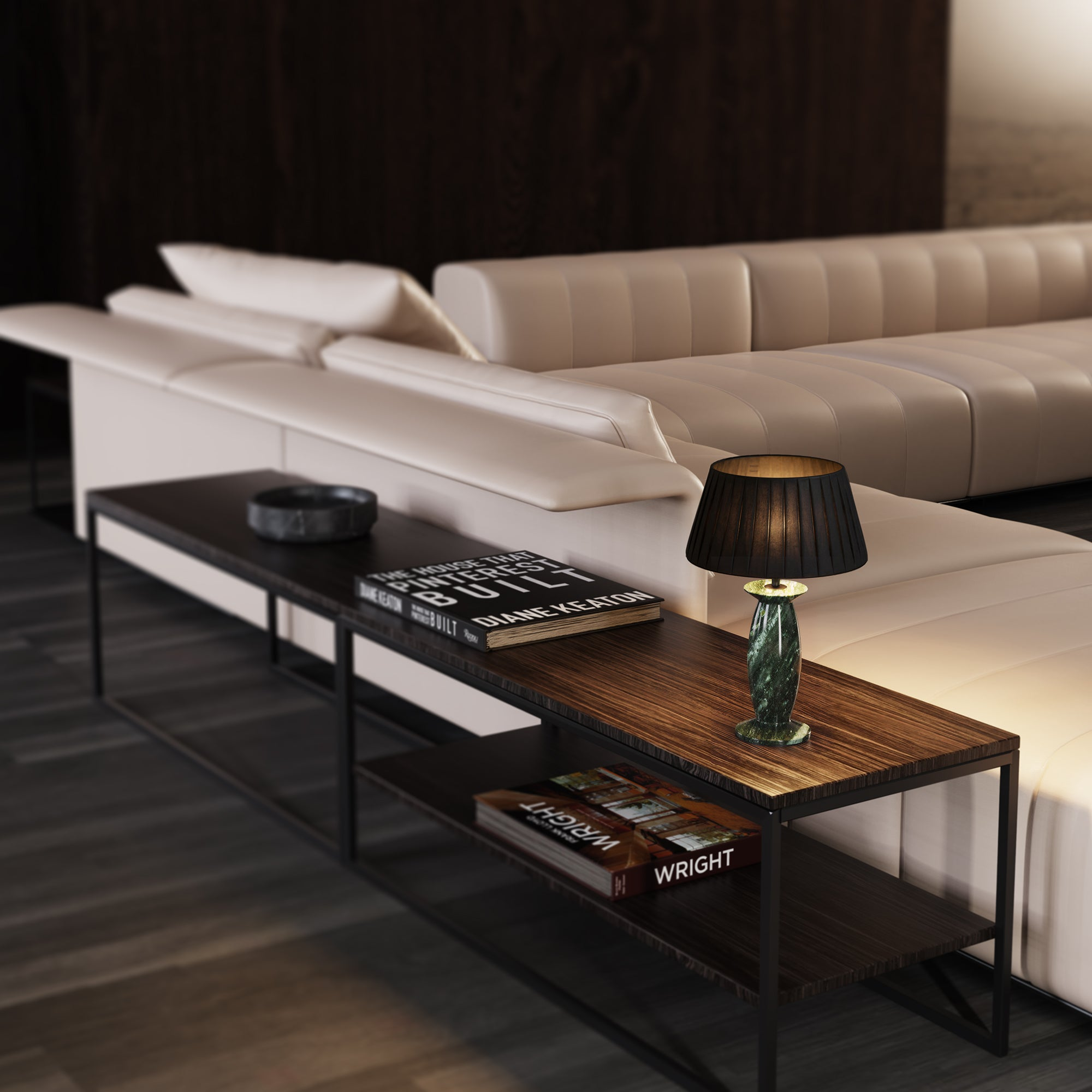 Ein Nachttisch aus Holz mit Büchern und Lampe neben einem hellen Ledersofa.