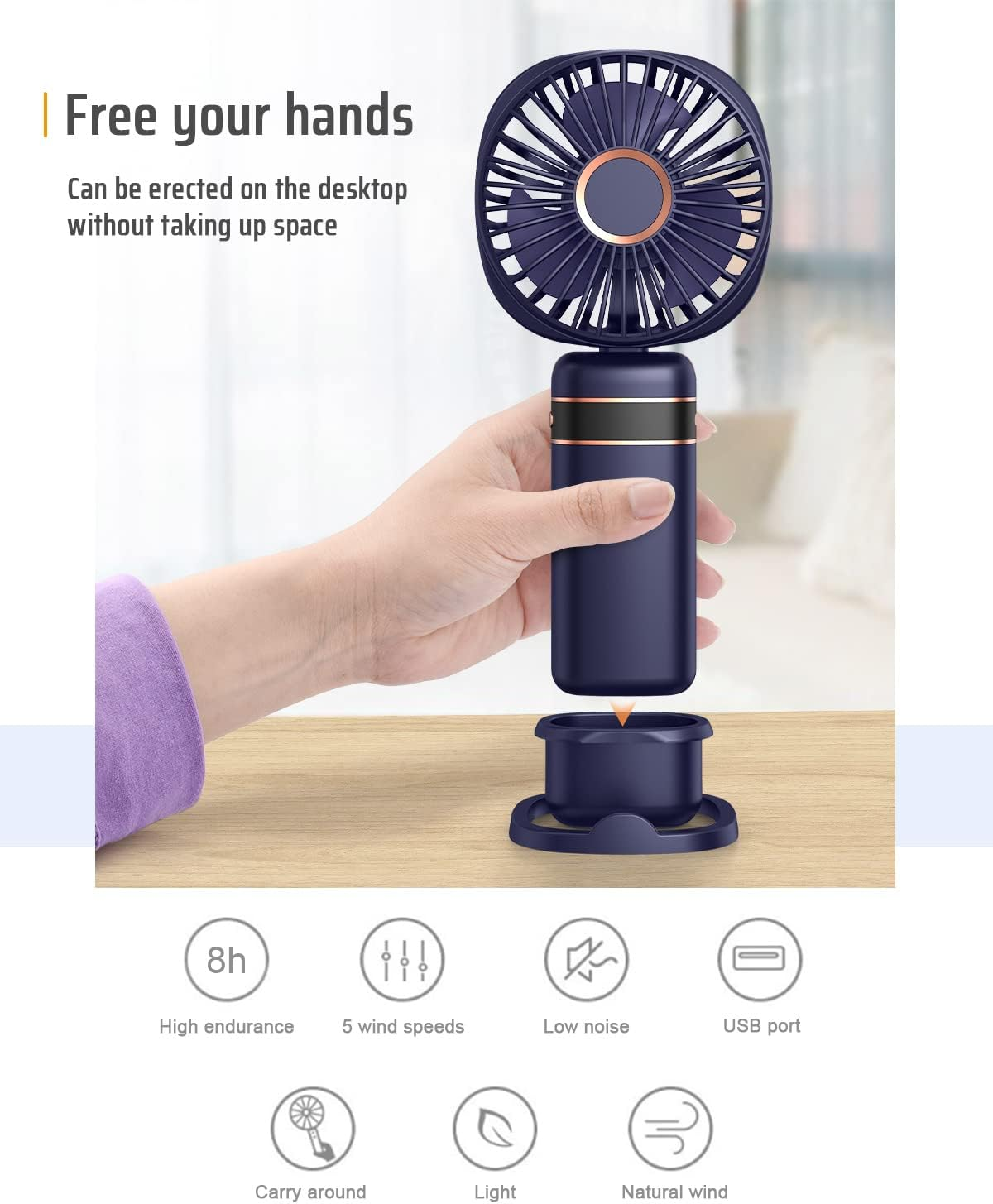 Eine Hand hält einen dunklen, tragbaren Ventilator mit einem dunklen Ständer.
