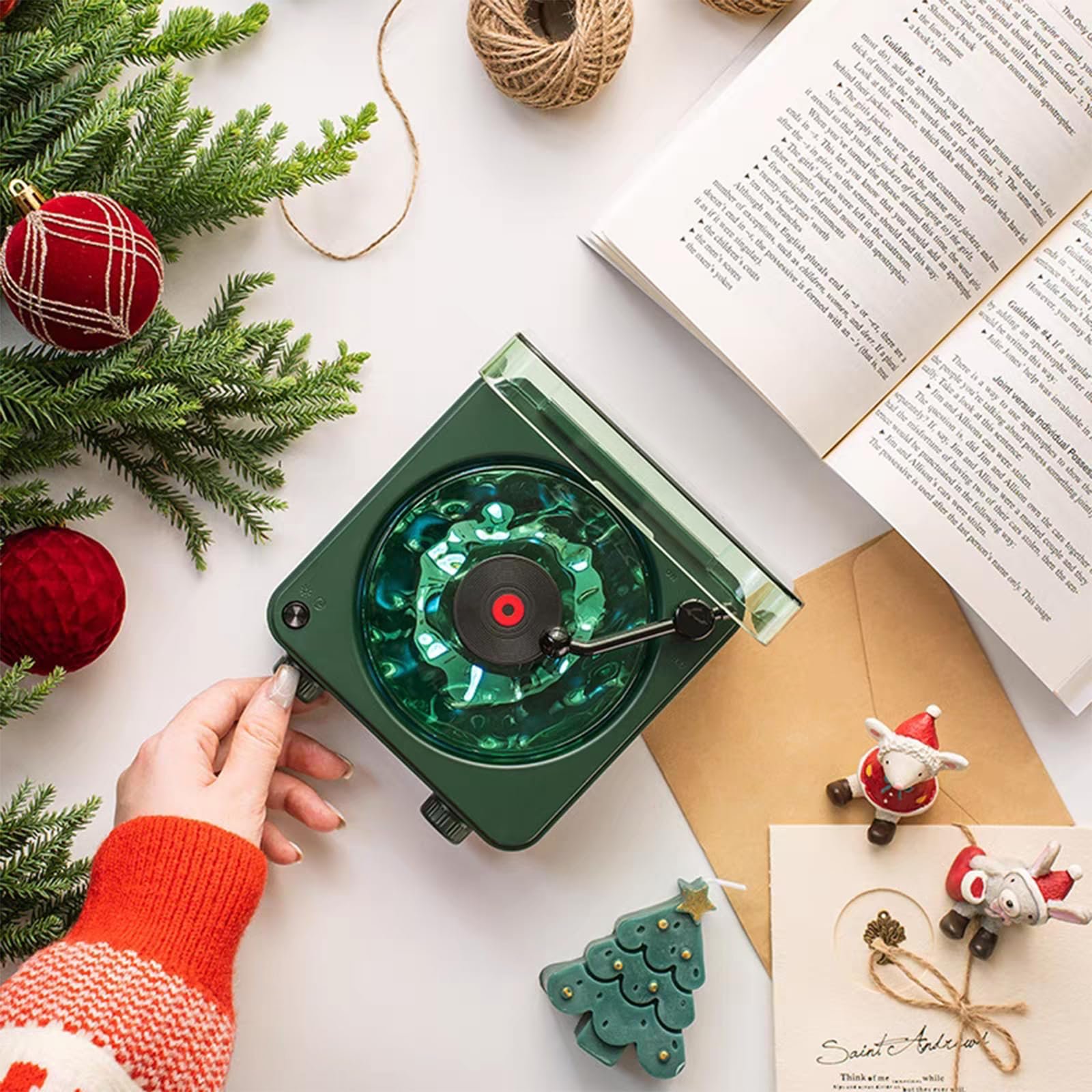 Grüner Plattenspieler mit Buch, Weihnachtskugeln und handgefertigten Figuren.