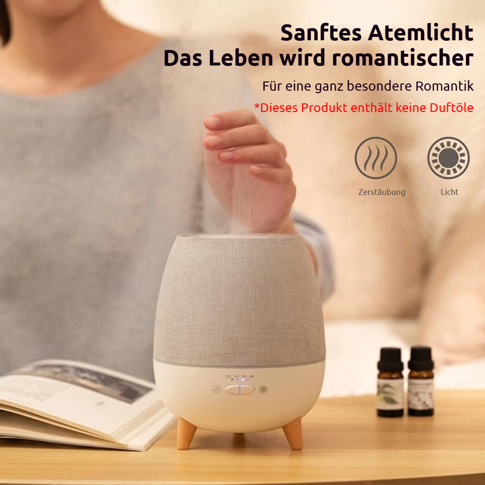 Ein Diffusor mit sanftem Licht und Dampf, zwei Ölfläschchen daneben.